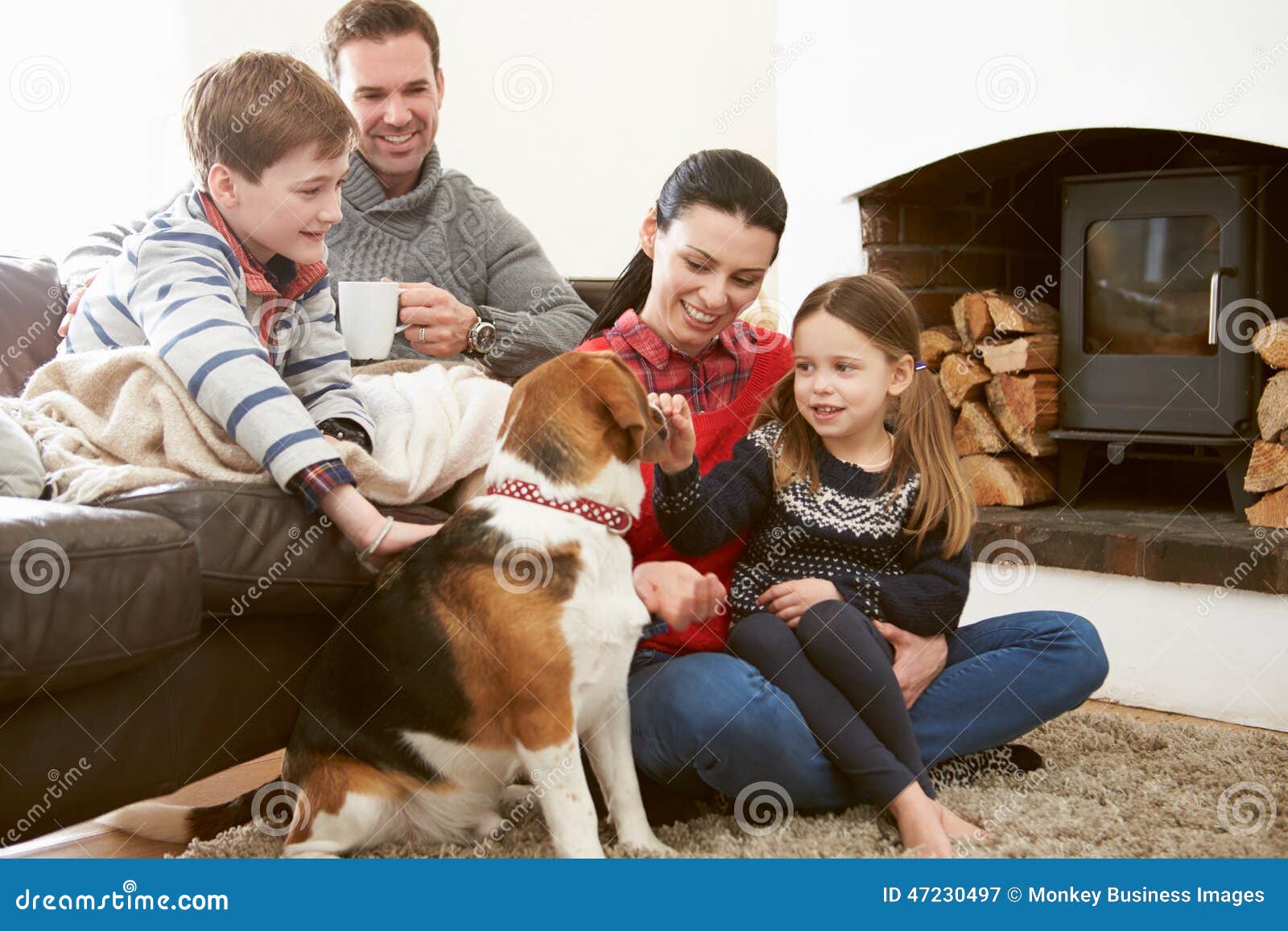 family relaxing indoors and stroking pet dog