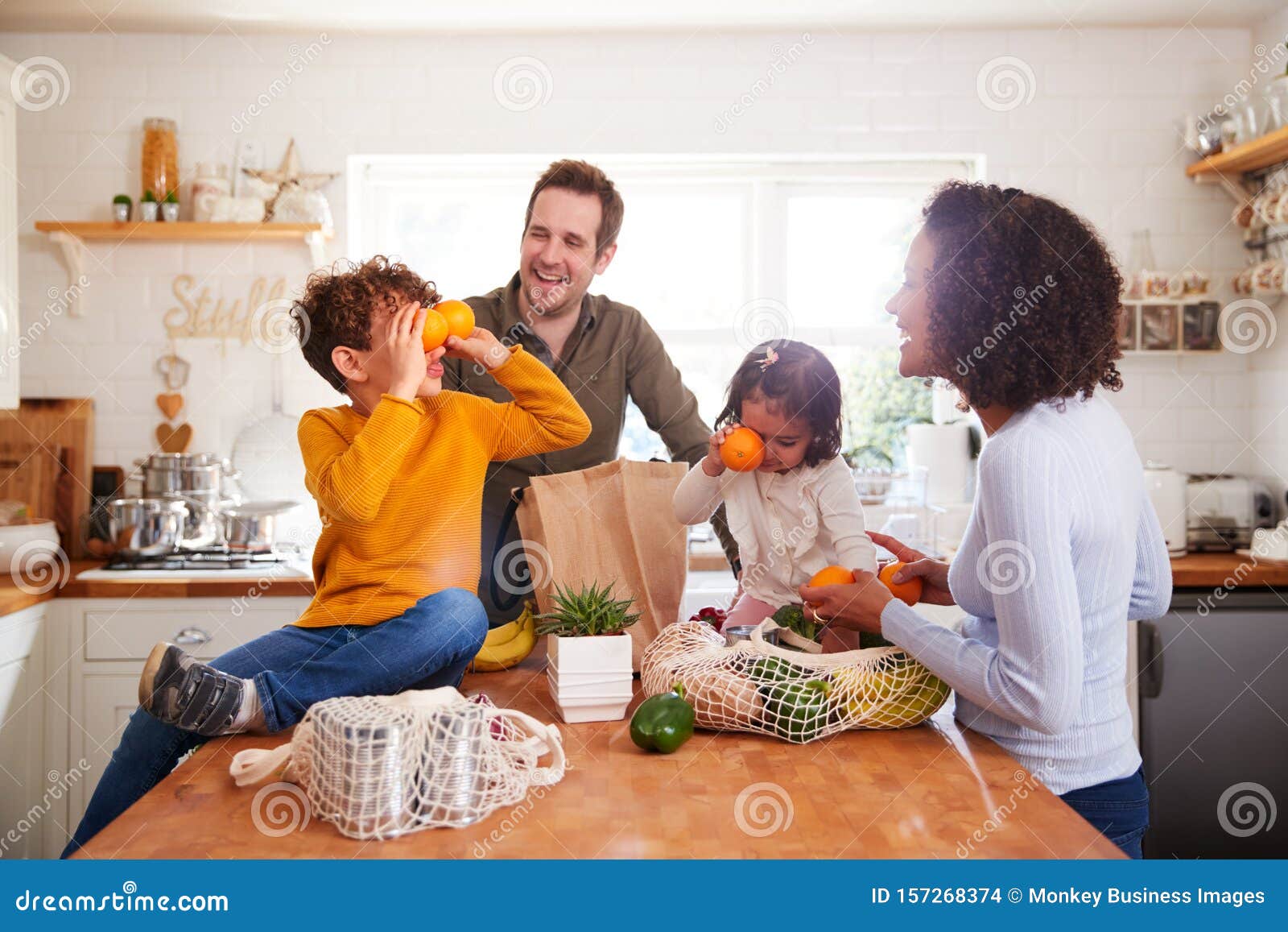 family returning home from shopping trip using plastic free bags unpacking groceries in kitchen