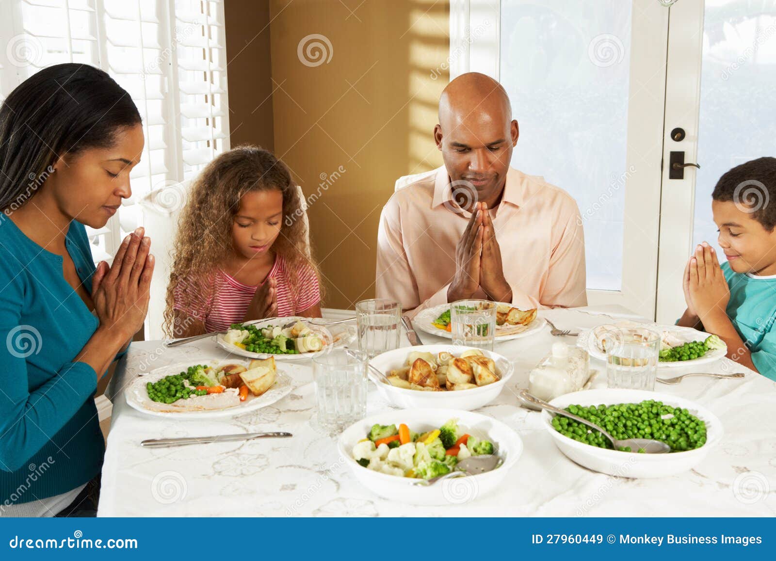 family saying grace before meal at home