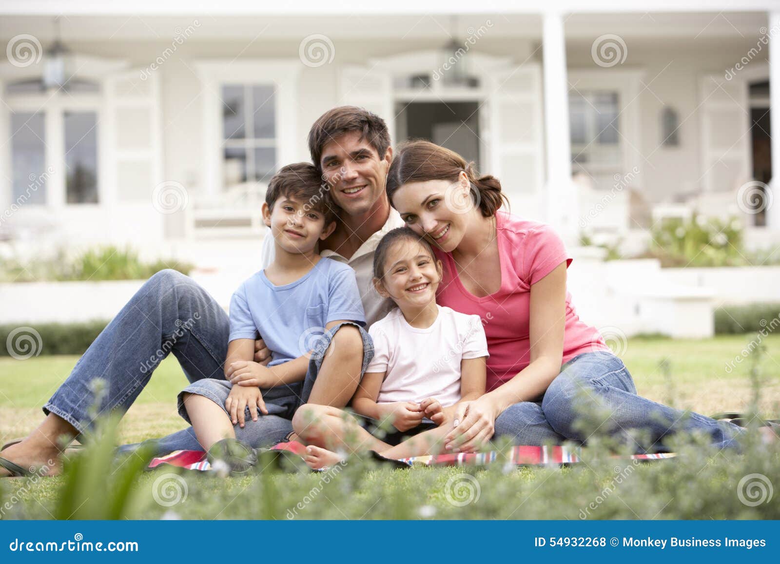 family sitting outside house on lawn