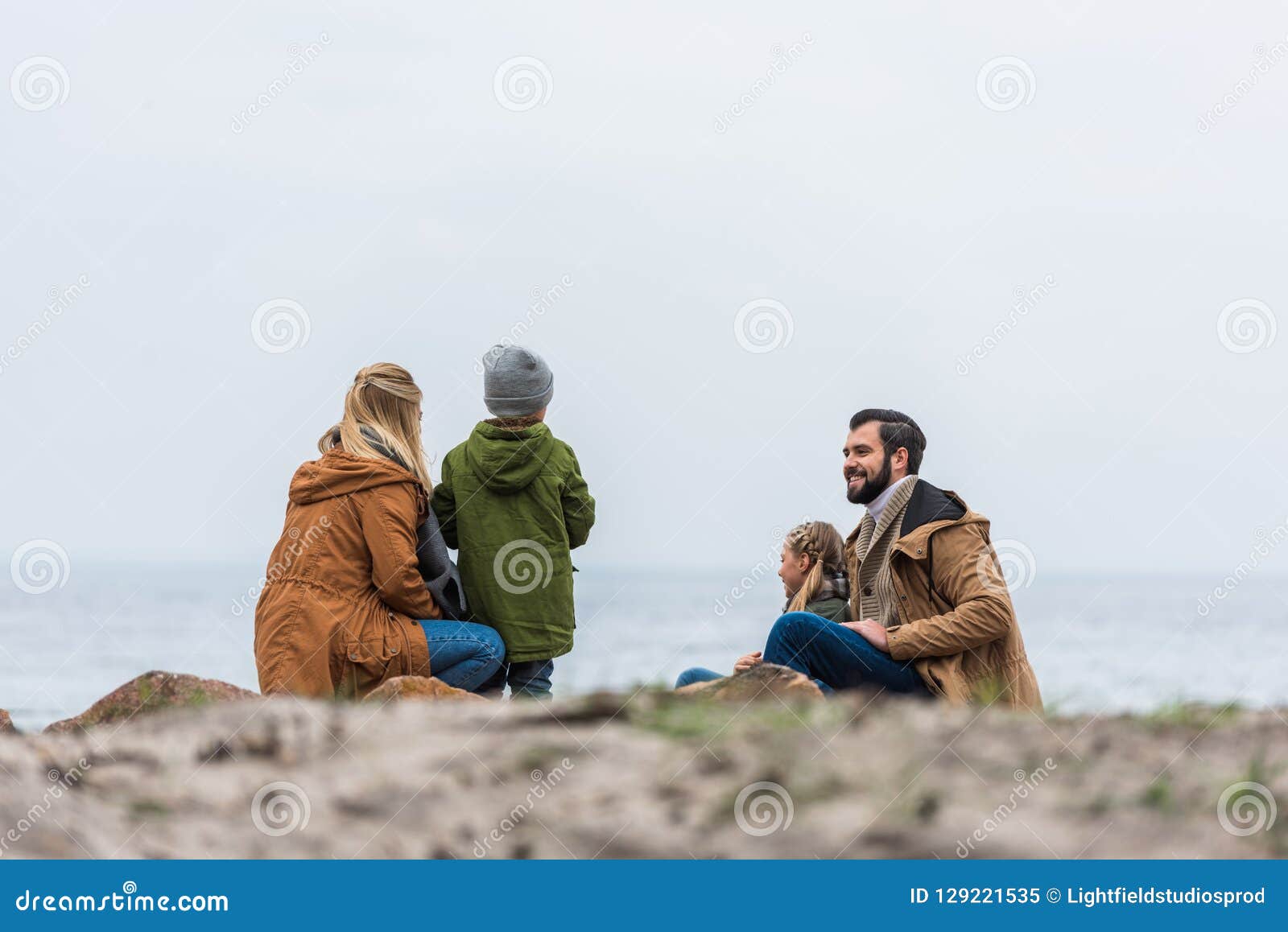 happy young family spending time on seashore on cold