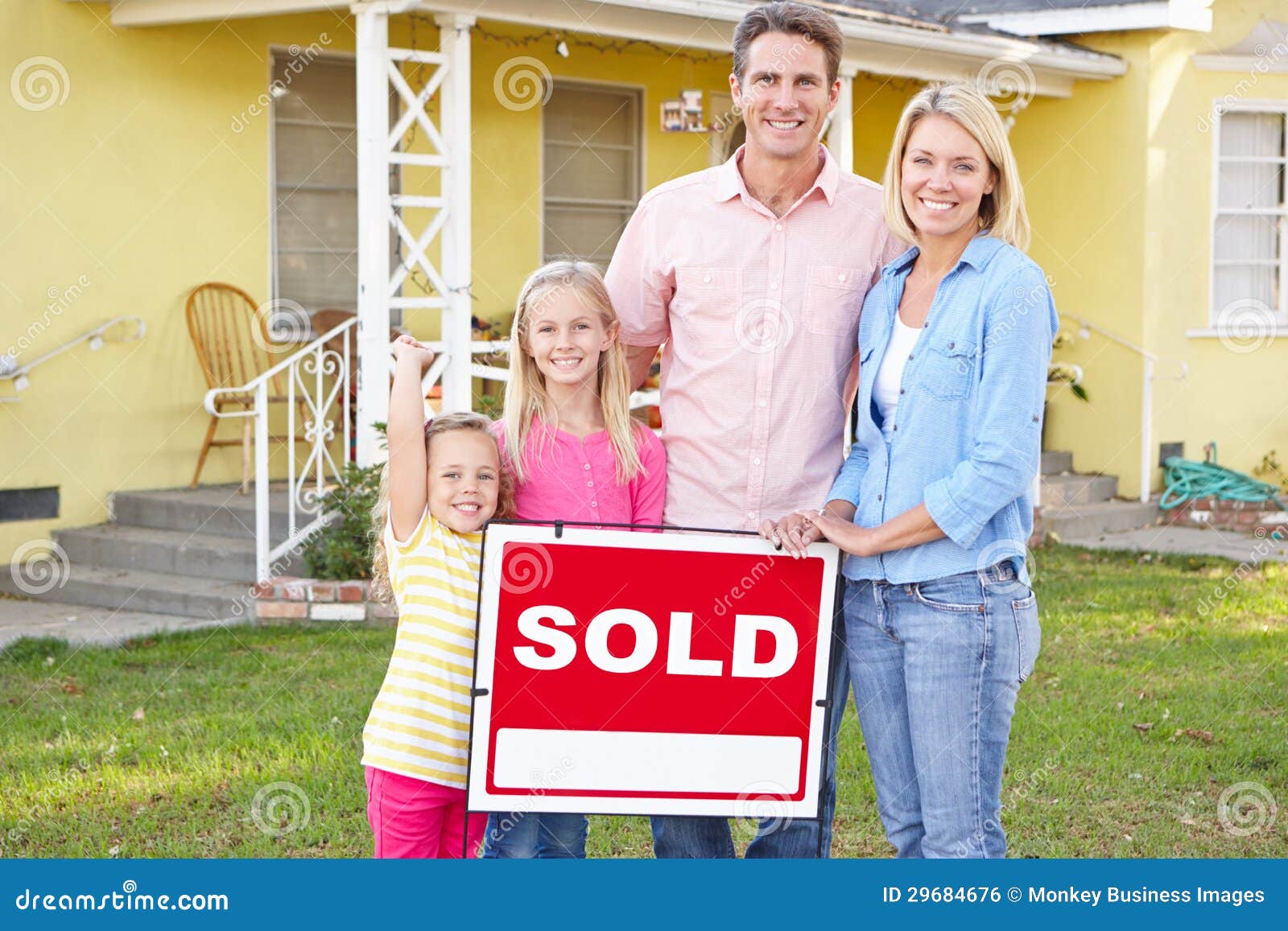 family standing by sold sign outside home