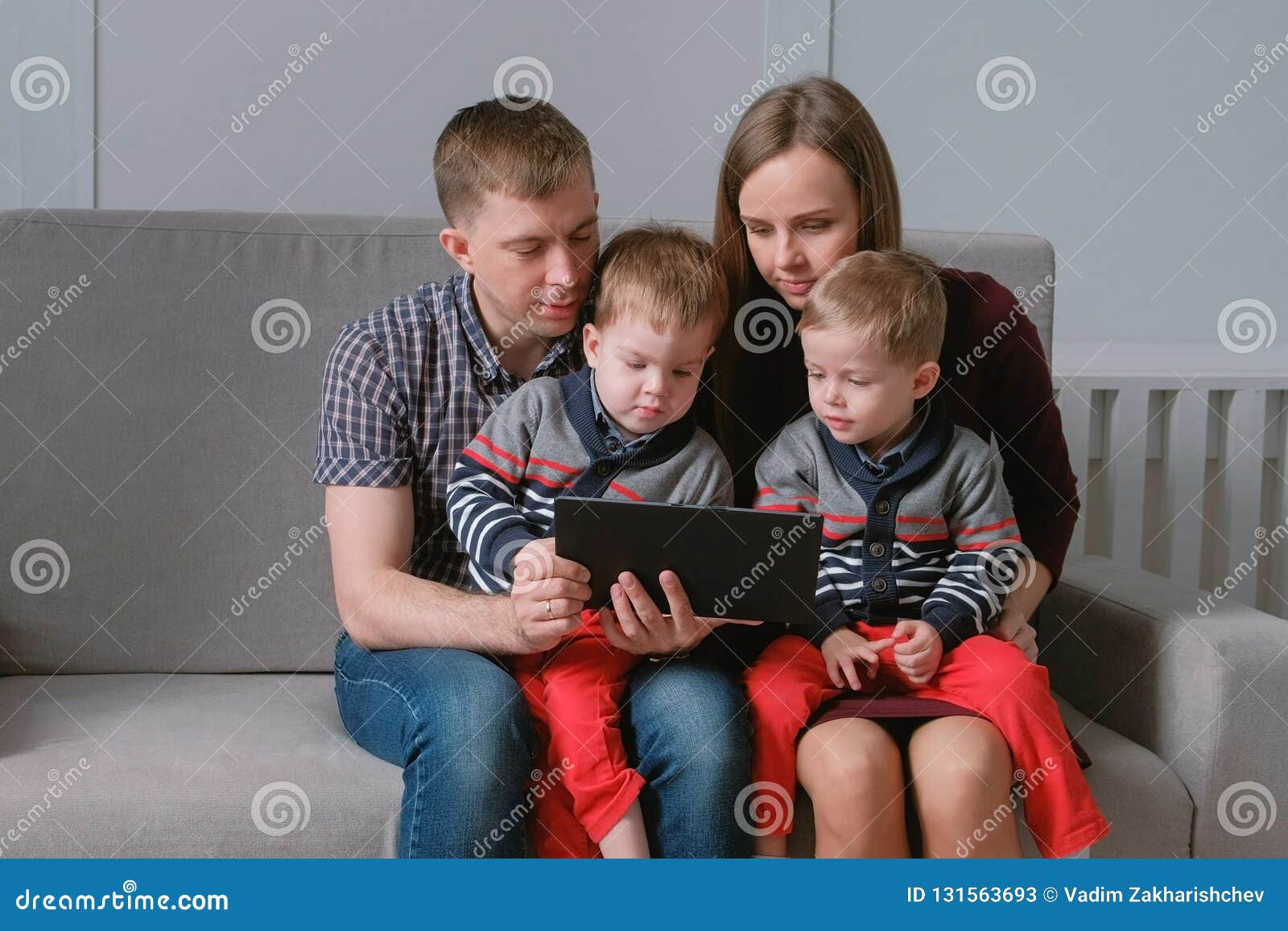 Family With Tablet Mom Dad And Two Sons Twins Looking At Tablet