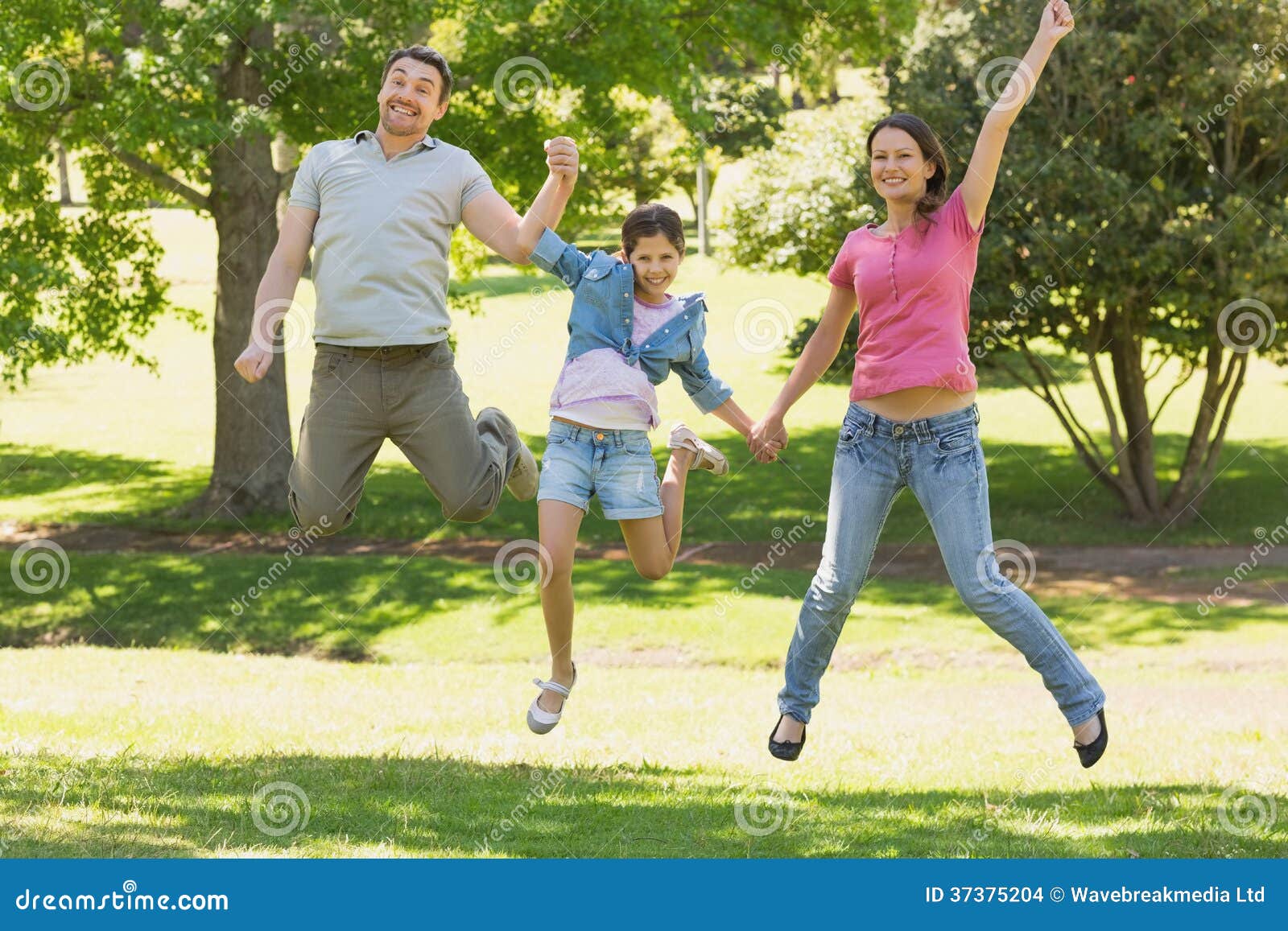 Family of Three Holding Hands and Jumping at Park Stock Photo Image