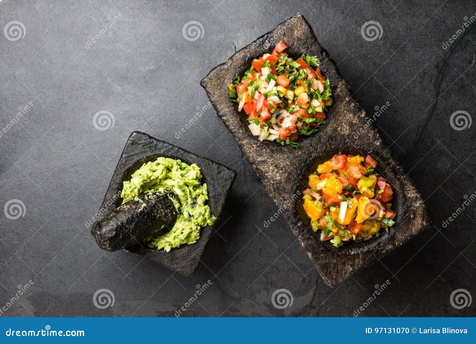 famous mexican sauces salsas - pico de gallo, avocado guacamole, salsa bandera mexicana in stone mortars on gray slate background