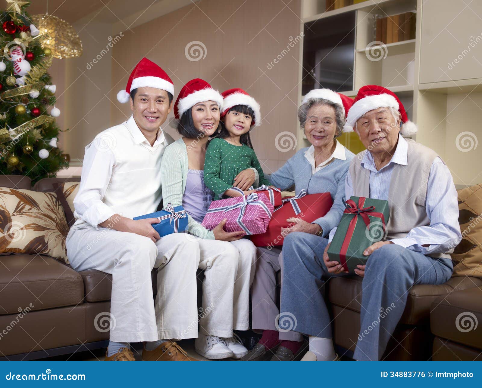 Família asiática com chapéus do Natal. Retrato home de uma família asiática com chapéus e presentes do Natal.