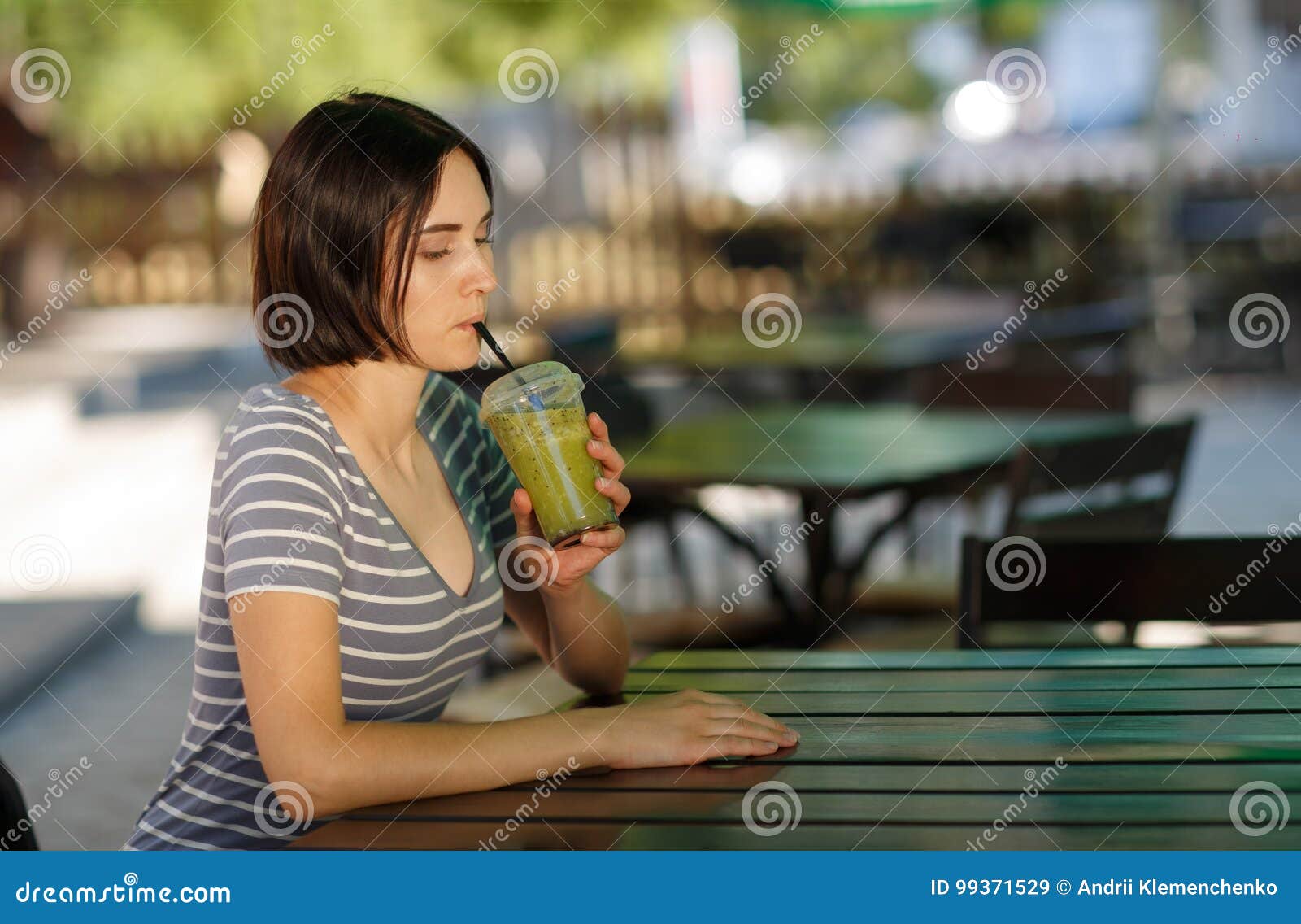 Positive Girl with a Smoothie. Smiling Woman Sitting at the Blurred ...