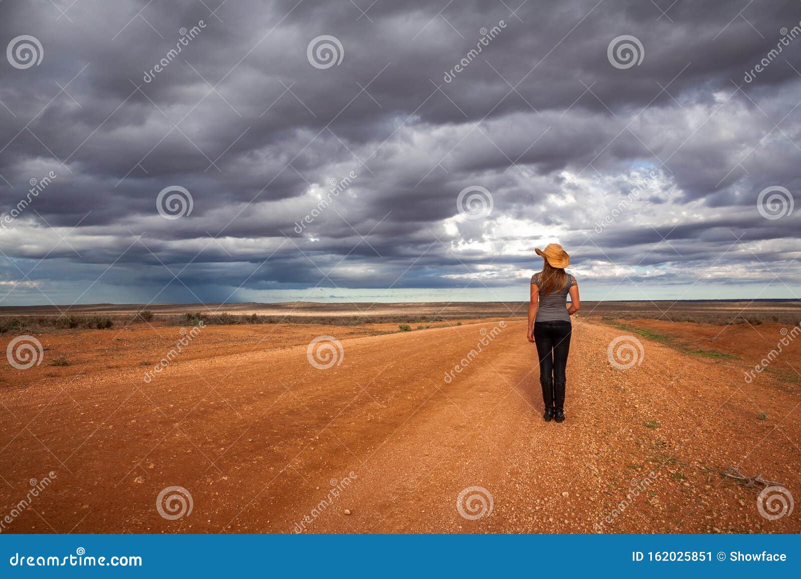farm girl watching storm over the arid desert