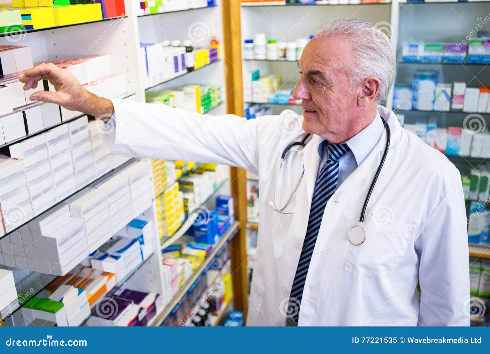 Farmacéutico que comprueba medicinas en farmacia. Farmacéutico en capa del laboratorio que comprueba medicinas en farmacia