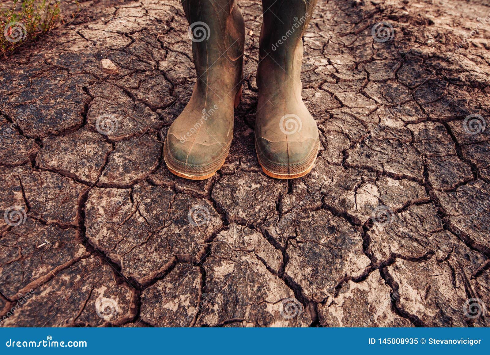farmer in rubber boots standing on dry soil ground
