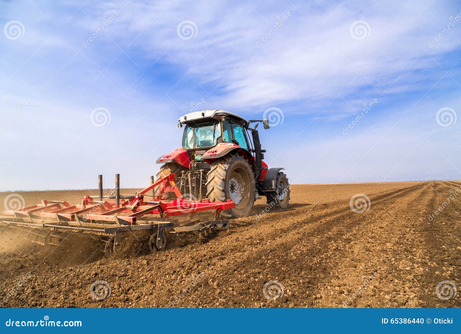 Farmer in Tractor Preparing Land with Seedbed Cultivator. Stock Photo