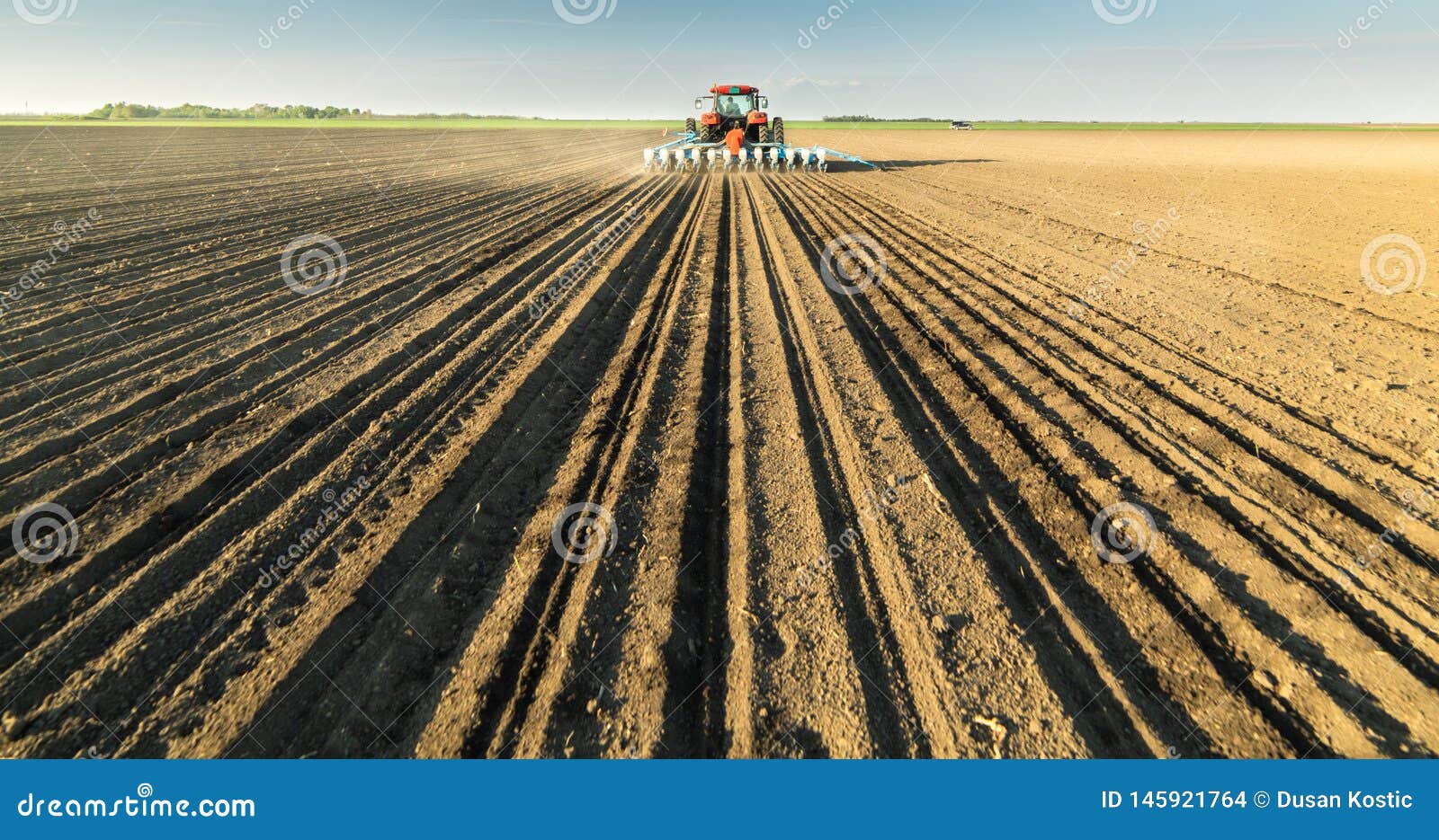 farmer with tractor seeding soy crops at agricultural field