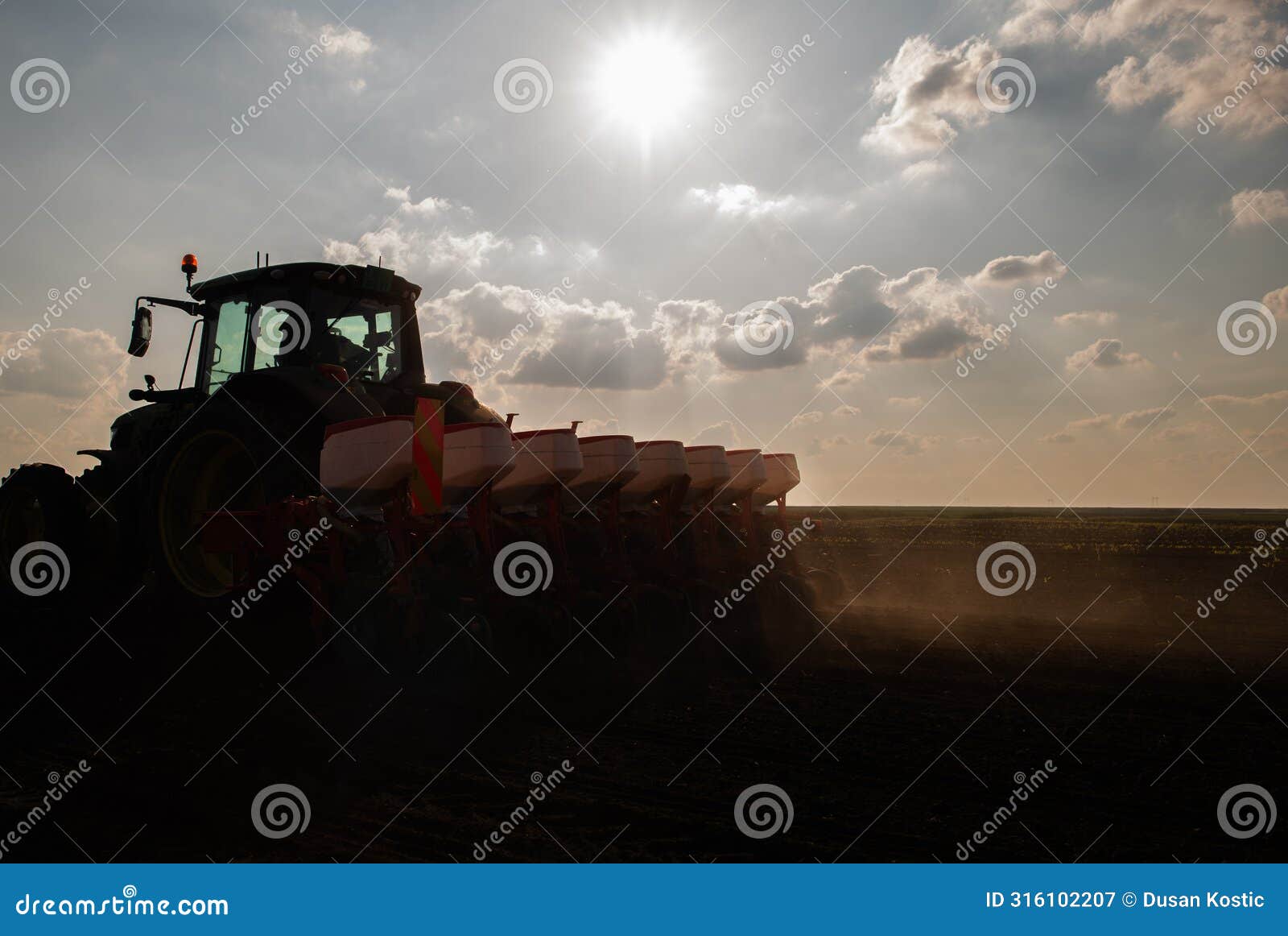 farmer with tractor seeding in sunset
