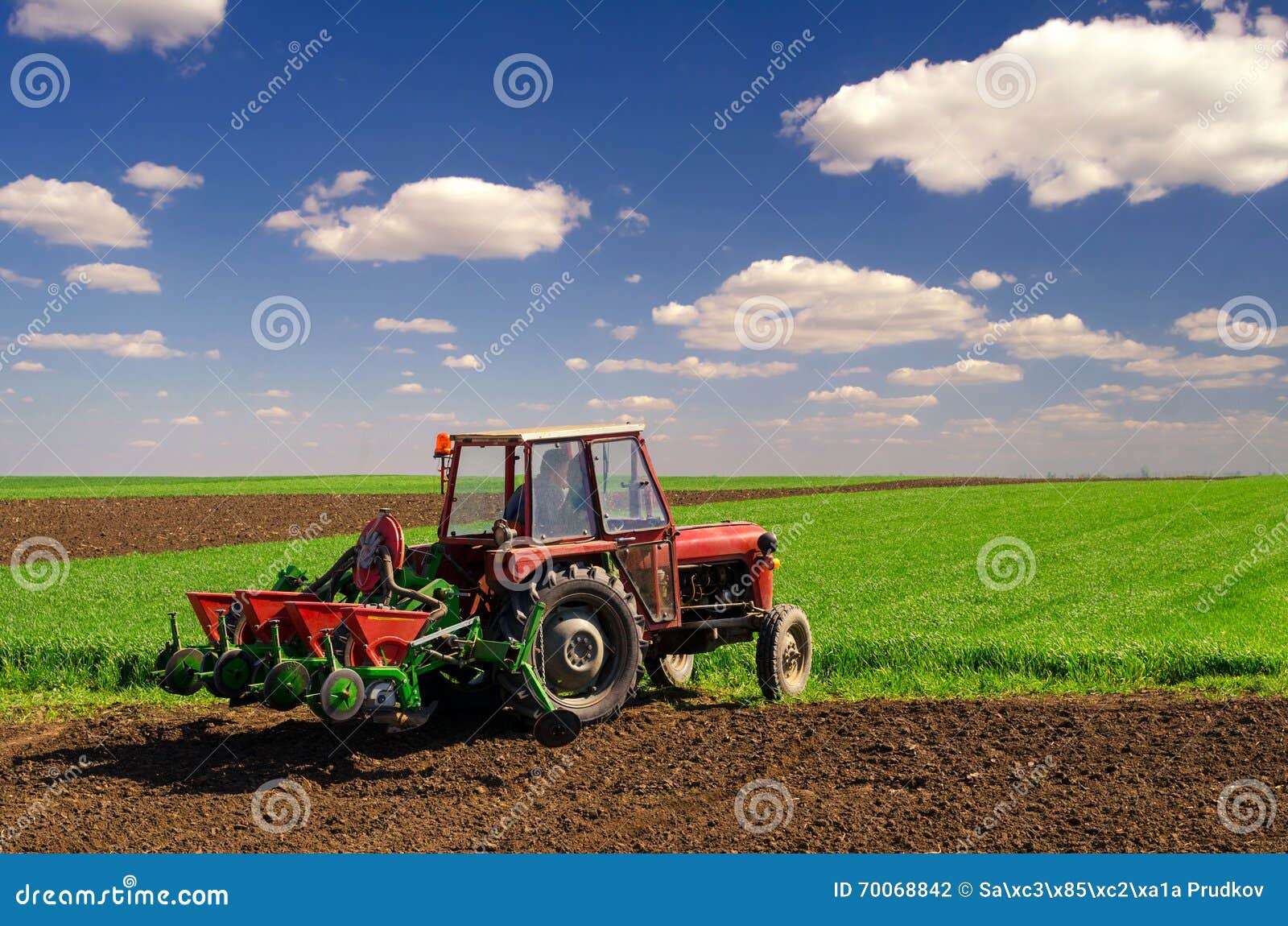 farmer with tractor sowing on agricultural fields in spring