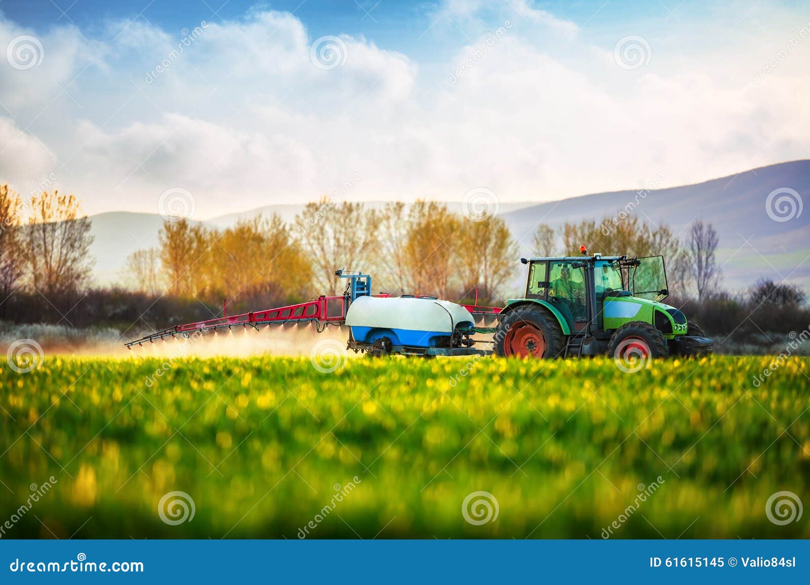 farming tractor plowing and spraying on the green field