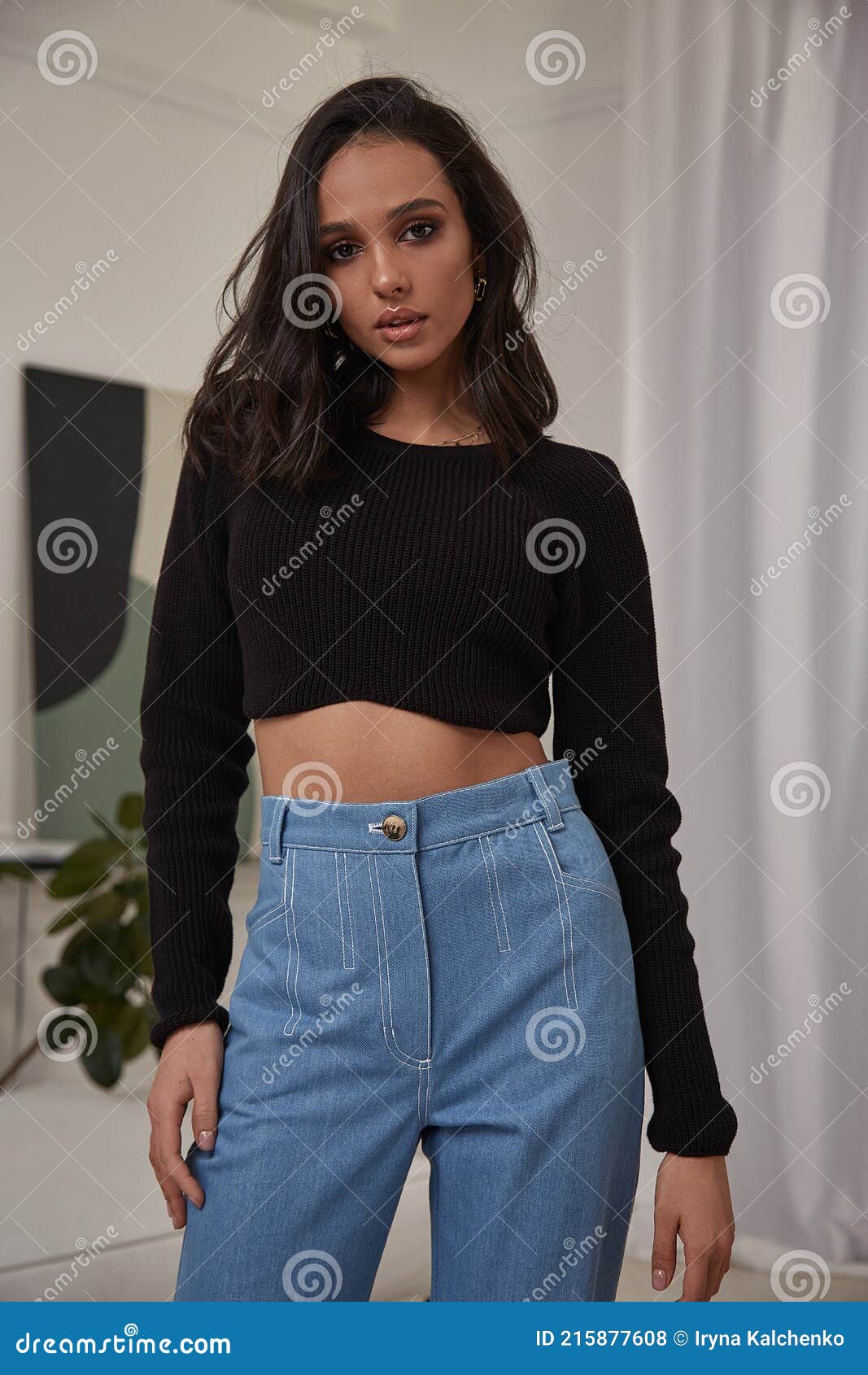 Stylish young girl in fashionable jeans clothes corrects her long hair at  sunset 9855428 Stock Photo at Vecteezy