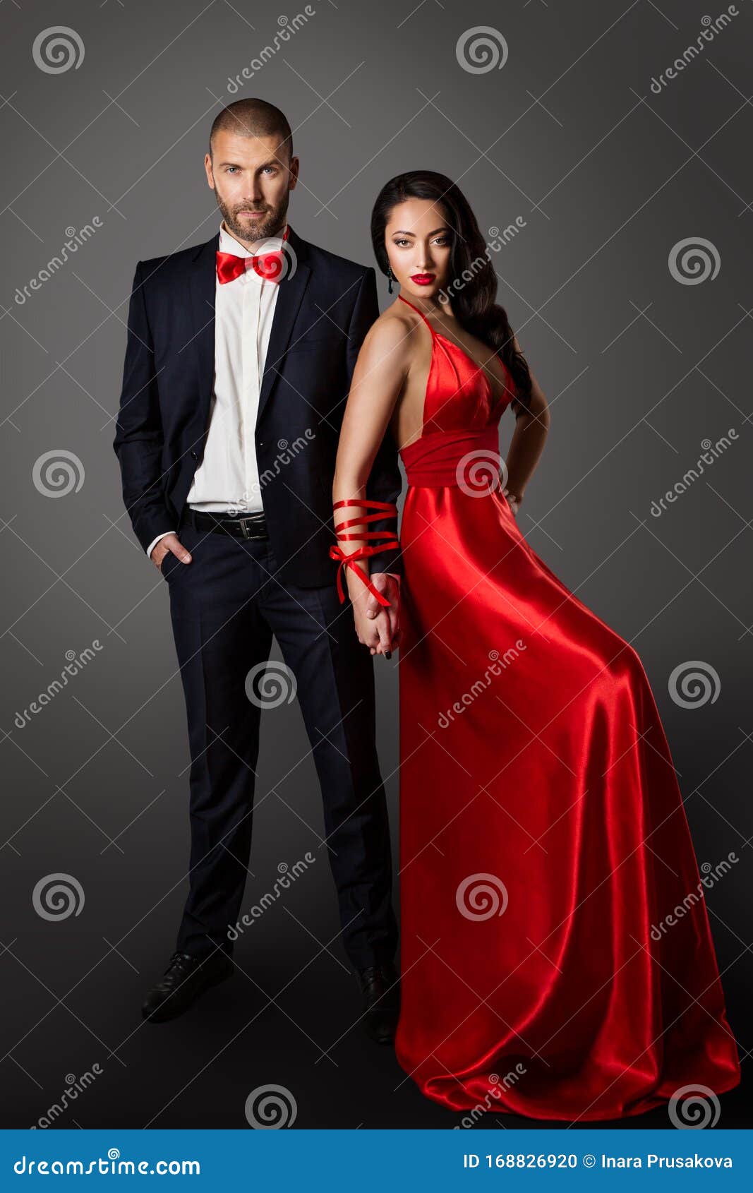 fashion couple, woman red dress and man in black suit, hands bounded