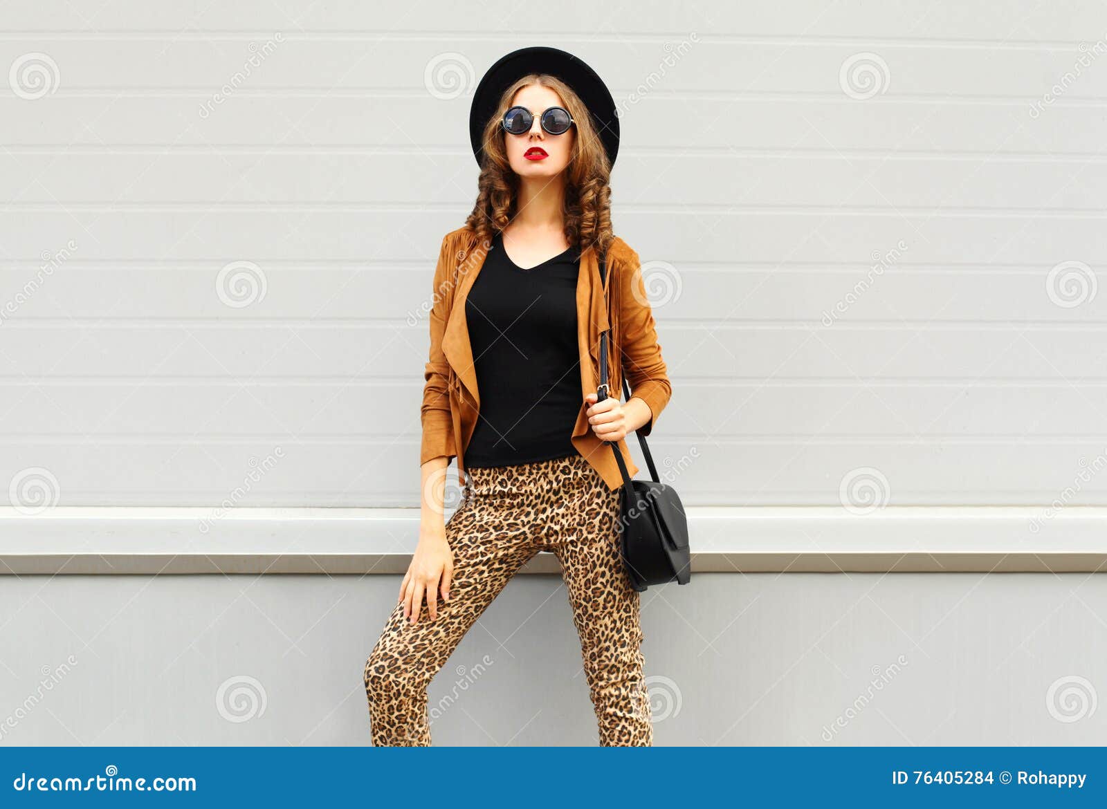 fashion look, pretty woman wearing a retro elegant hat, sunglasses, brown jacket and black handbag over background