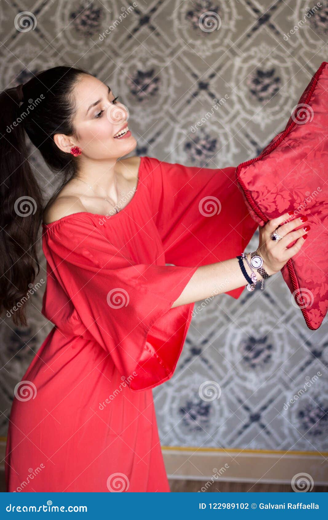 fashion model with red satin dress playing with a pillow