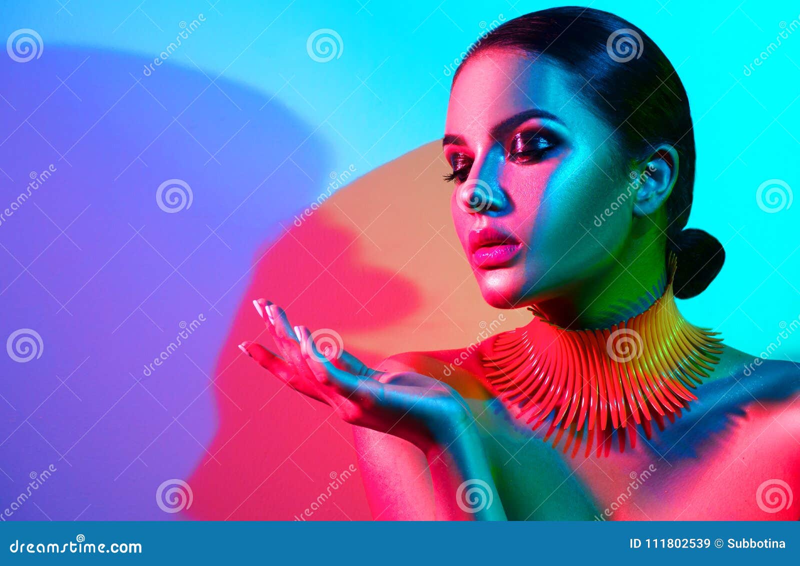 fashion model woman in colorful bright lights with trendy makeup and manicure posing