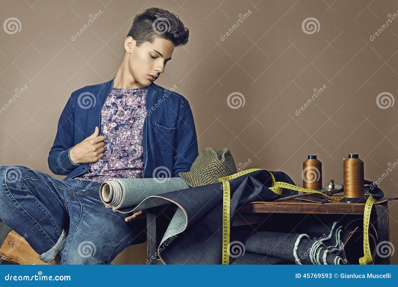 fashion portrait of handsome young man with tools for sewing den