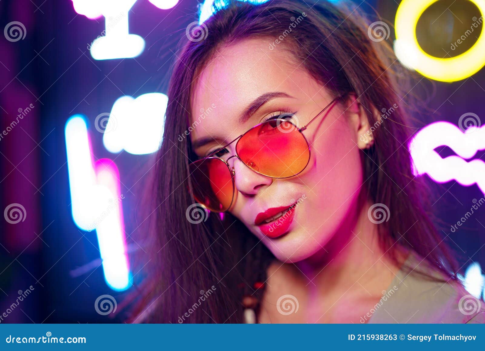 Fashion Portrait of a Young Woman in Sunglasses Posing Near Neon Signs ...