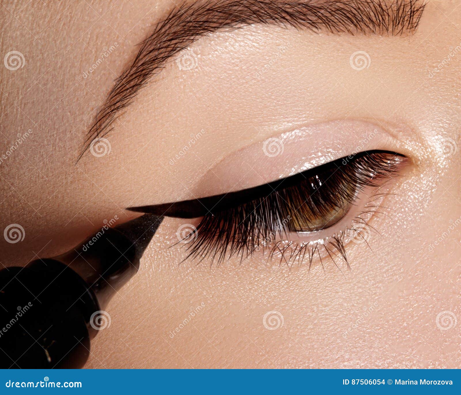 fashion woman applying eyeliner on eyelid, eyelash. using makeup brush,  black line. professional make-up artist