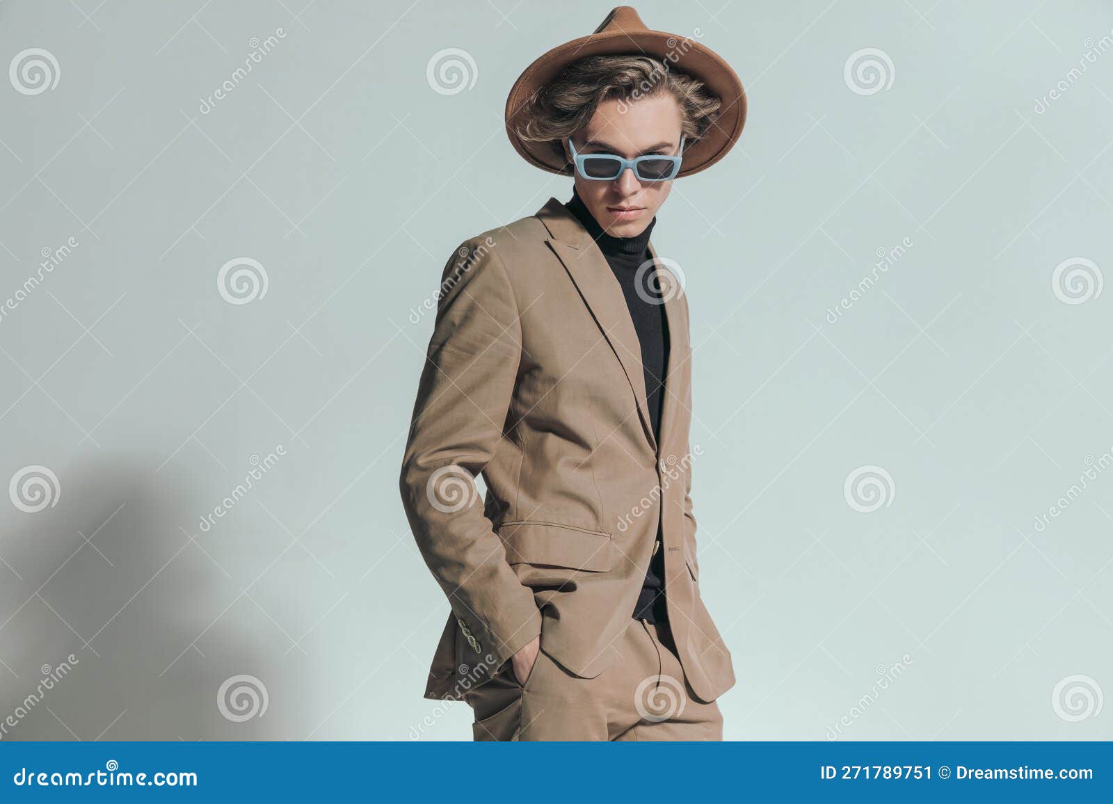 Fashion Young Guy with Sunglasses and Hat Posing with Hands in Pockets