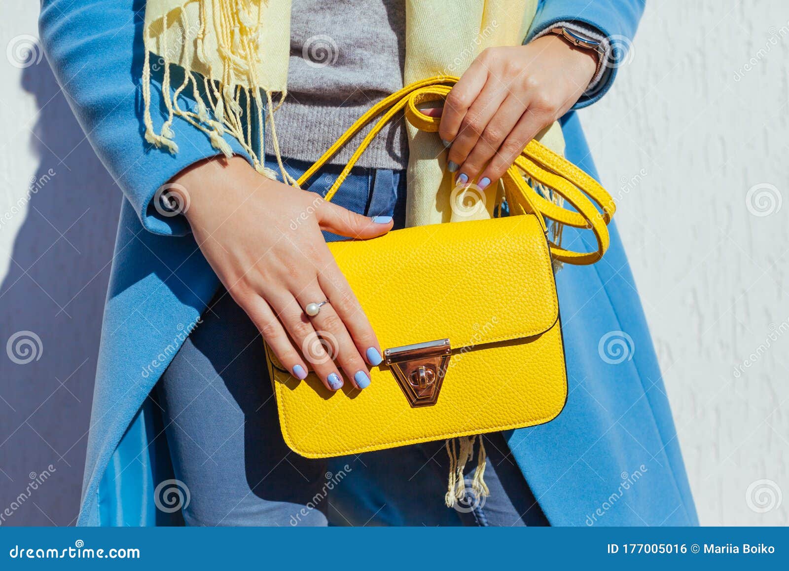 fashion. young woman holding stylish handbag and wearing trendy blue coat. spring female clothes and accessories