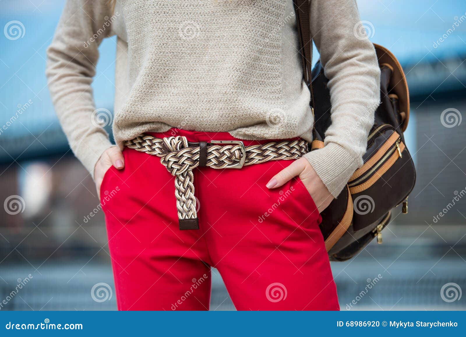 fashionable women`s casual spring outfit with red pants, cardigan, modern belt and bag