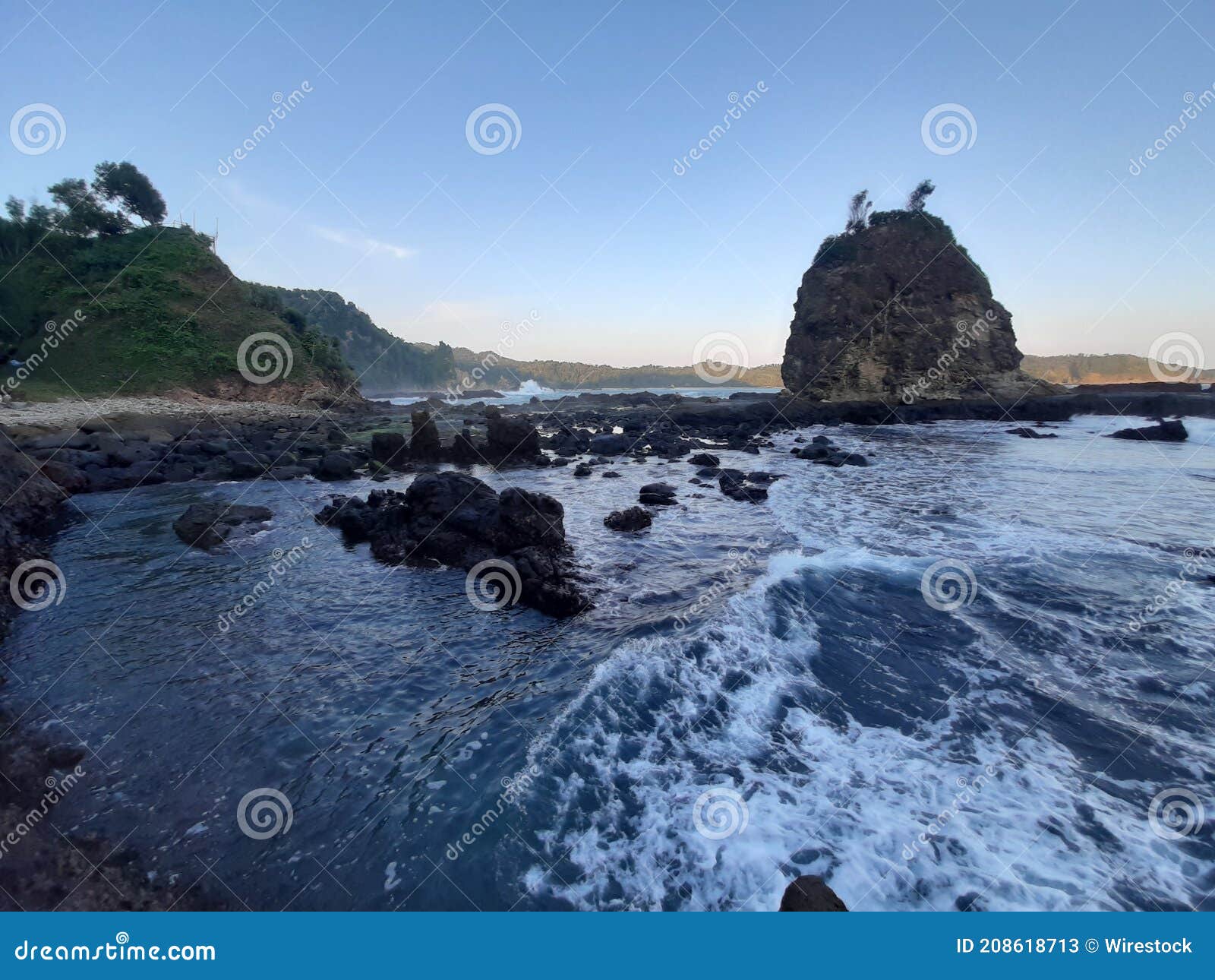 fast streaming ocean water in front ot a rock hill at watu lumbung beach