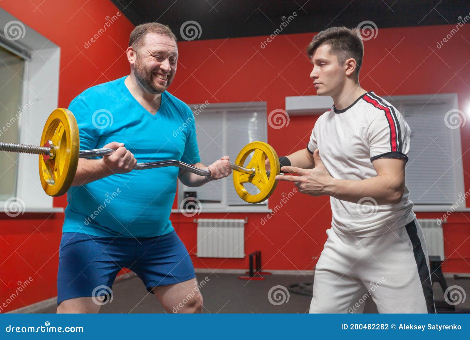 A Fat Man in the Gym Performs Barbell Lifting Exercises at the Limit of His Powers Under the