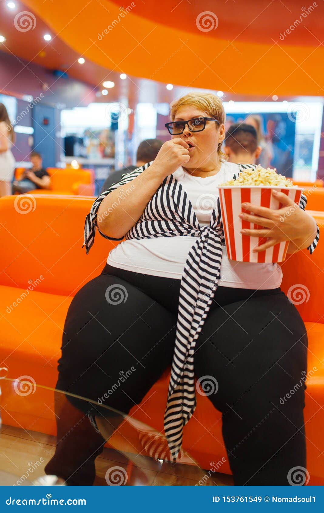 Woman with big thighs holding a larg bag of popcorn Stock Photo