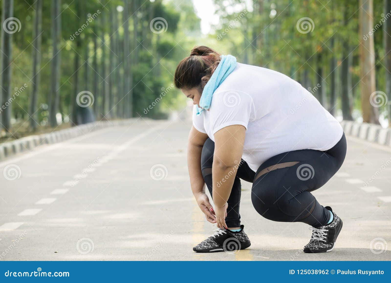 fat woman tying her shoelaces on the road