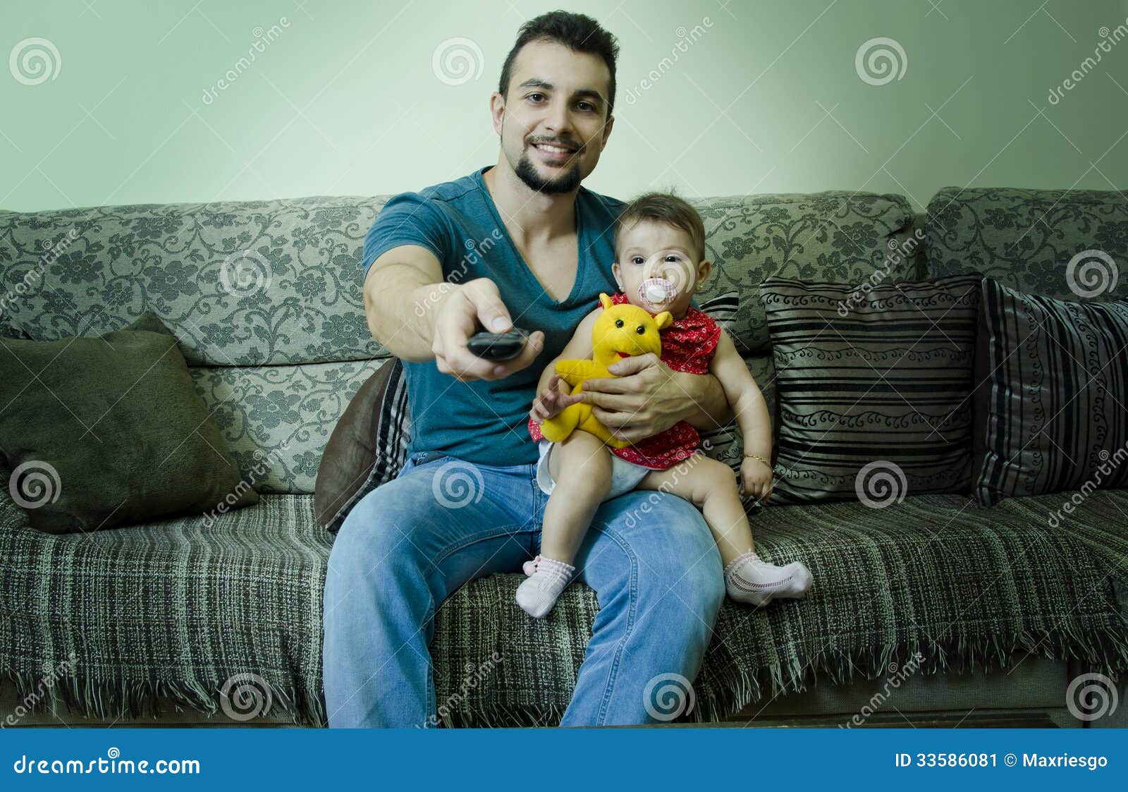 father baby watching tv holds pacifier remote control 33586081