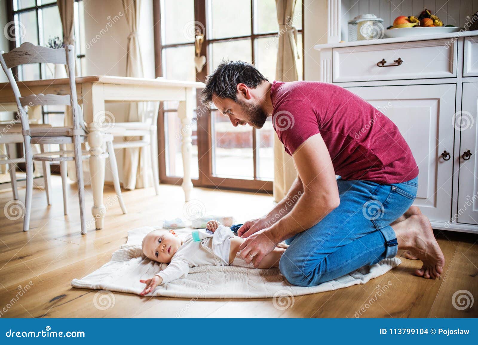 father changing a baby girl at home.