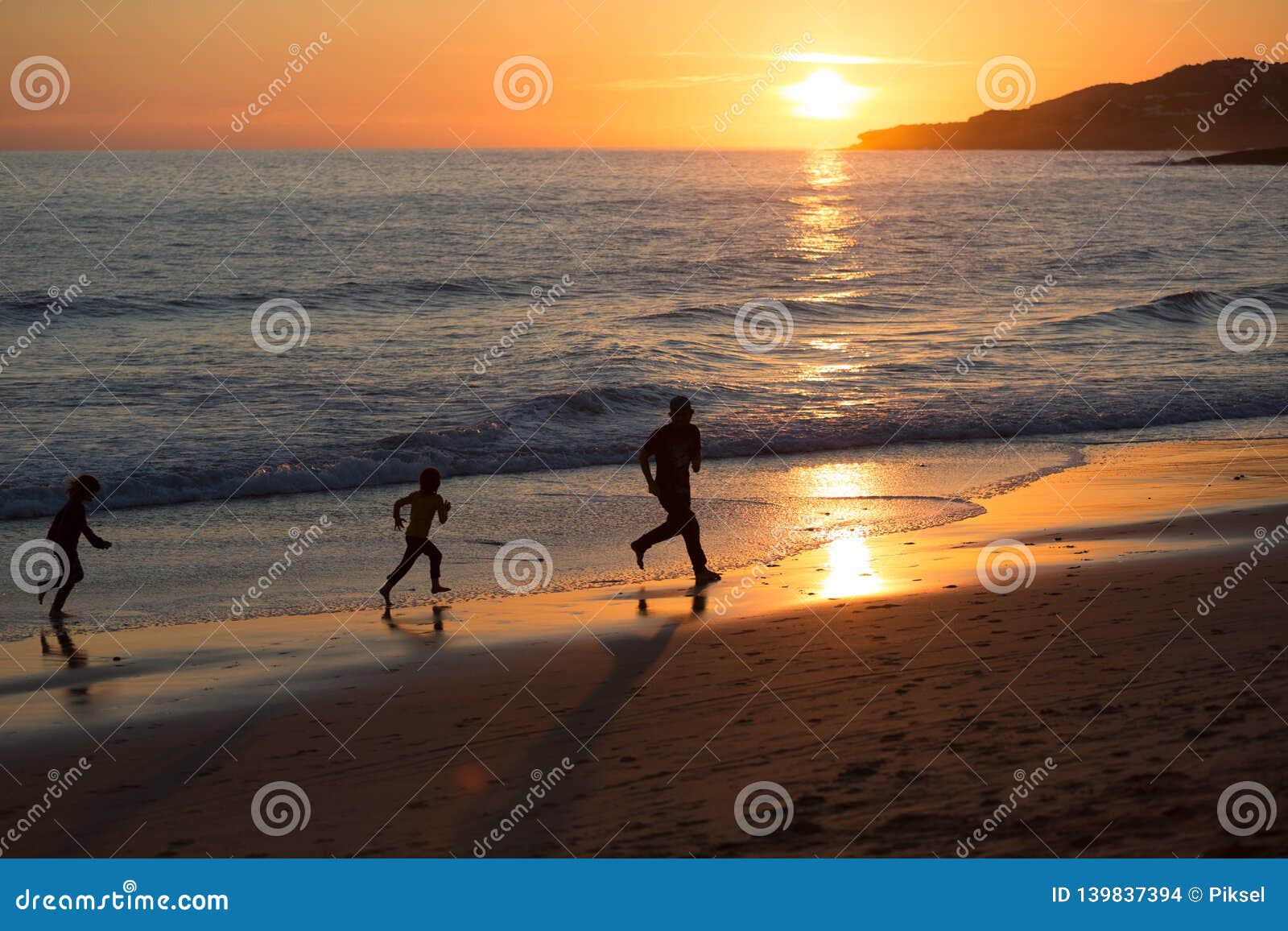 father and children running on the beach during sunset, praia da luz, portugal