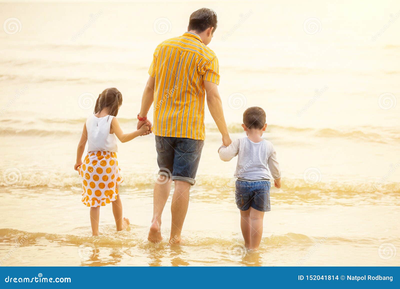 father and children  walking into the  beach holiday .  two kids one dad . rear back view