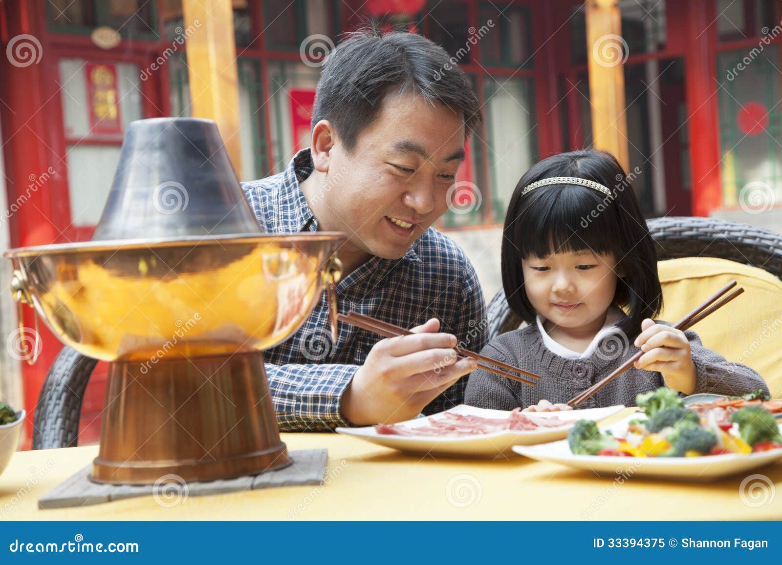 father and daughter eating chinese food outside