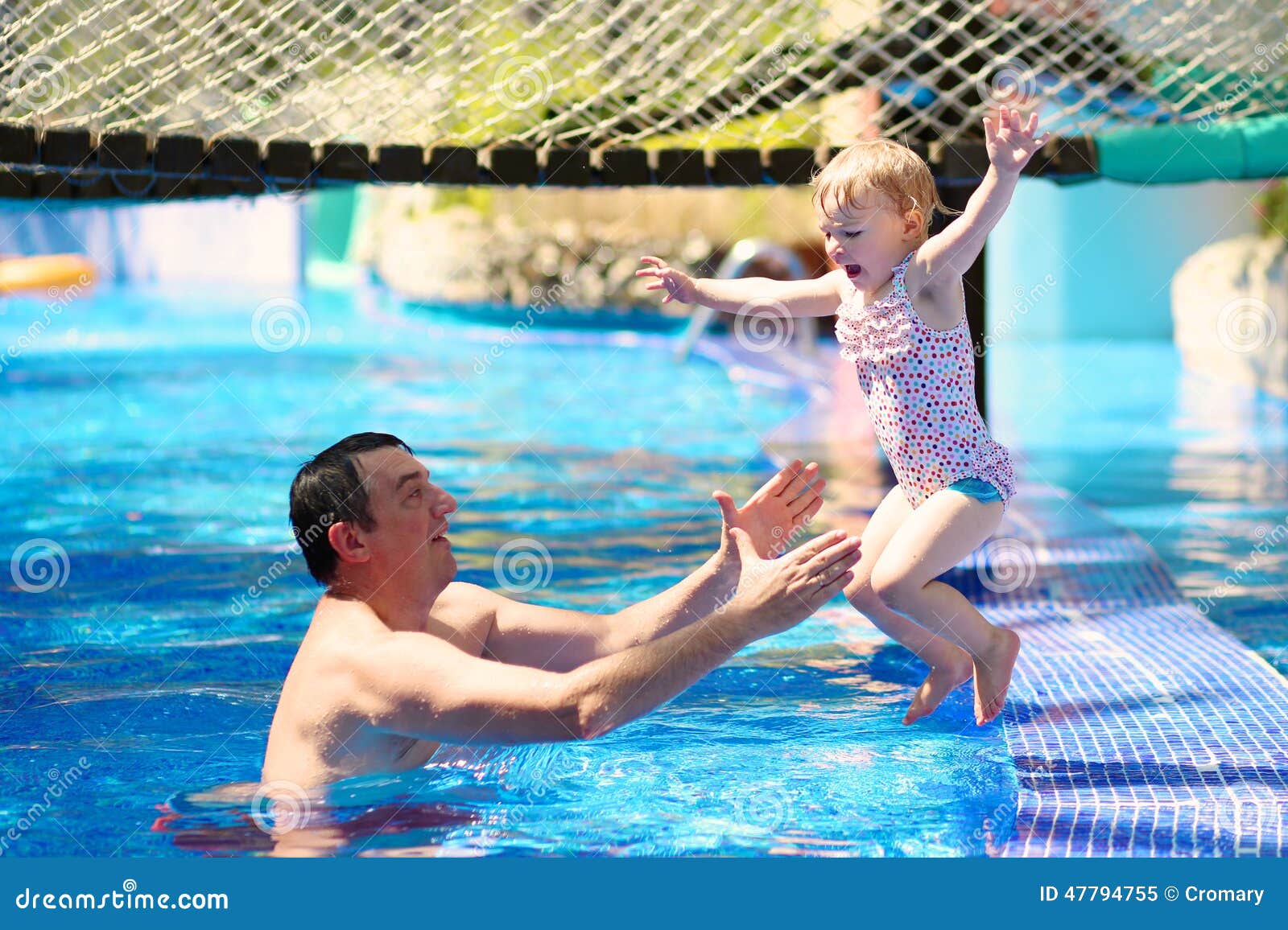 Father and daughter enjoying swimming pool. Happy family, active father with little child, adorable toddler girl, having fun together in outdoors swimming pool in water park during sunny summer sea vacation in tropical resort