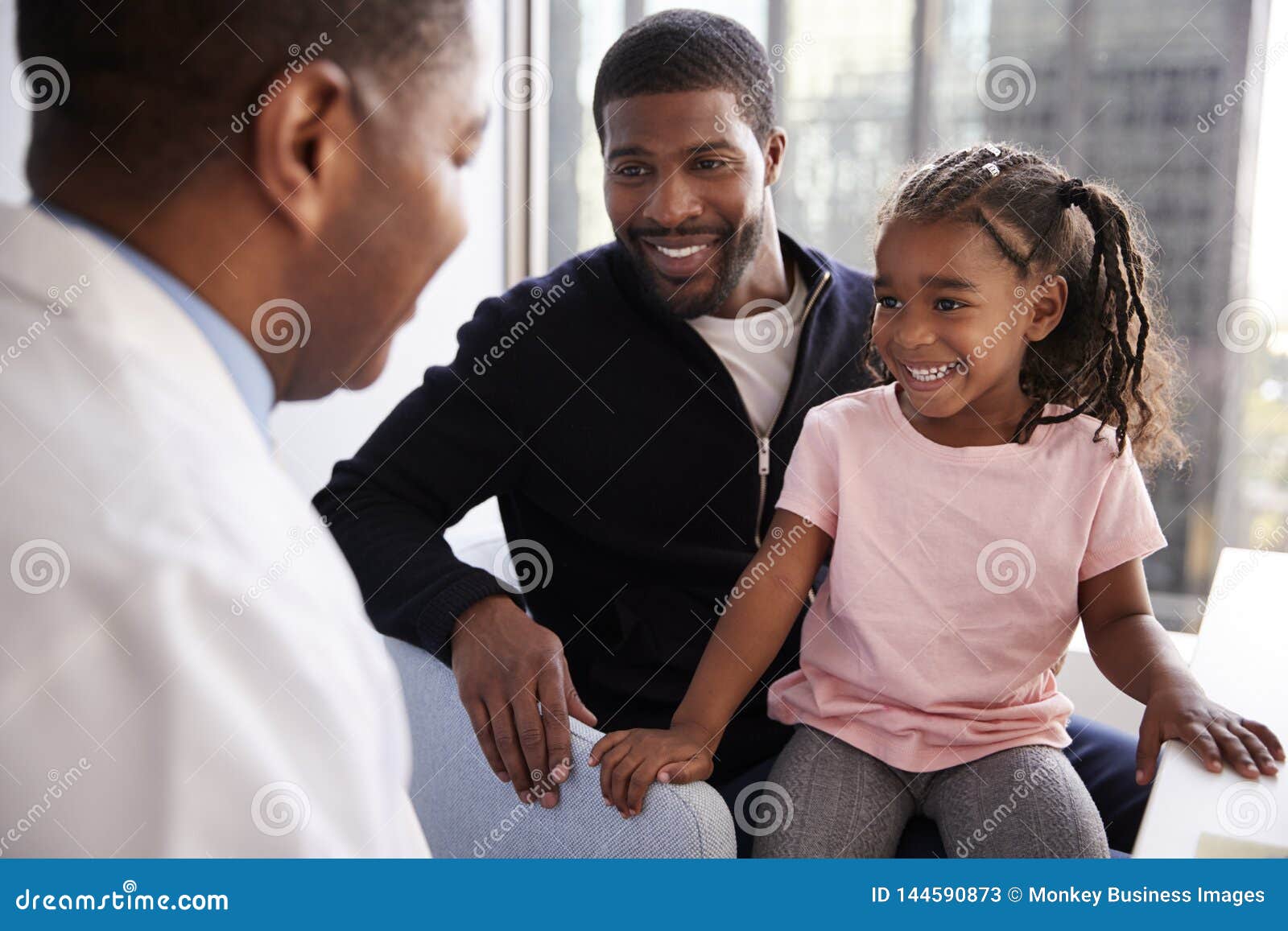 father and daughter having consultation with female pediatrician in hospital office