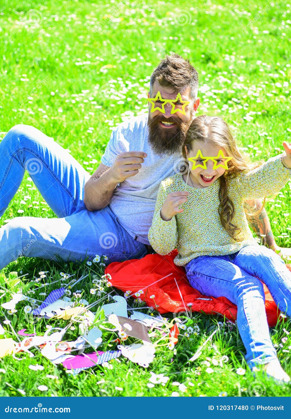 father and daughter sits on grass at grassplot, green background. child and dad posing with star d eyeglases photo