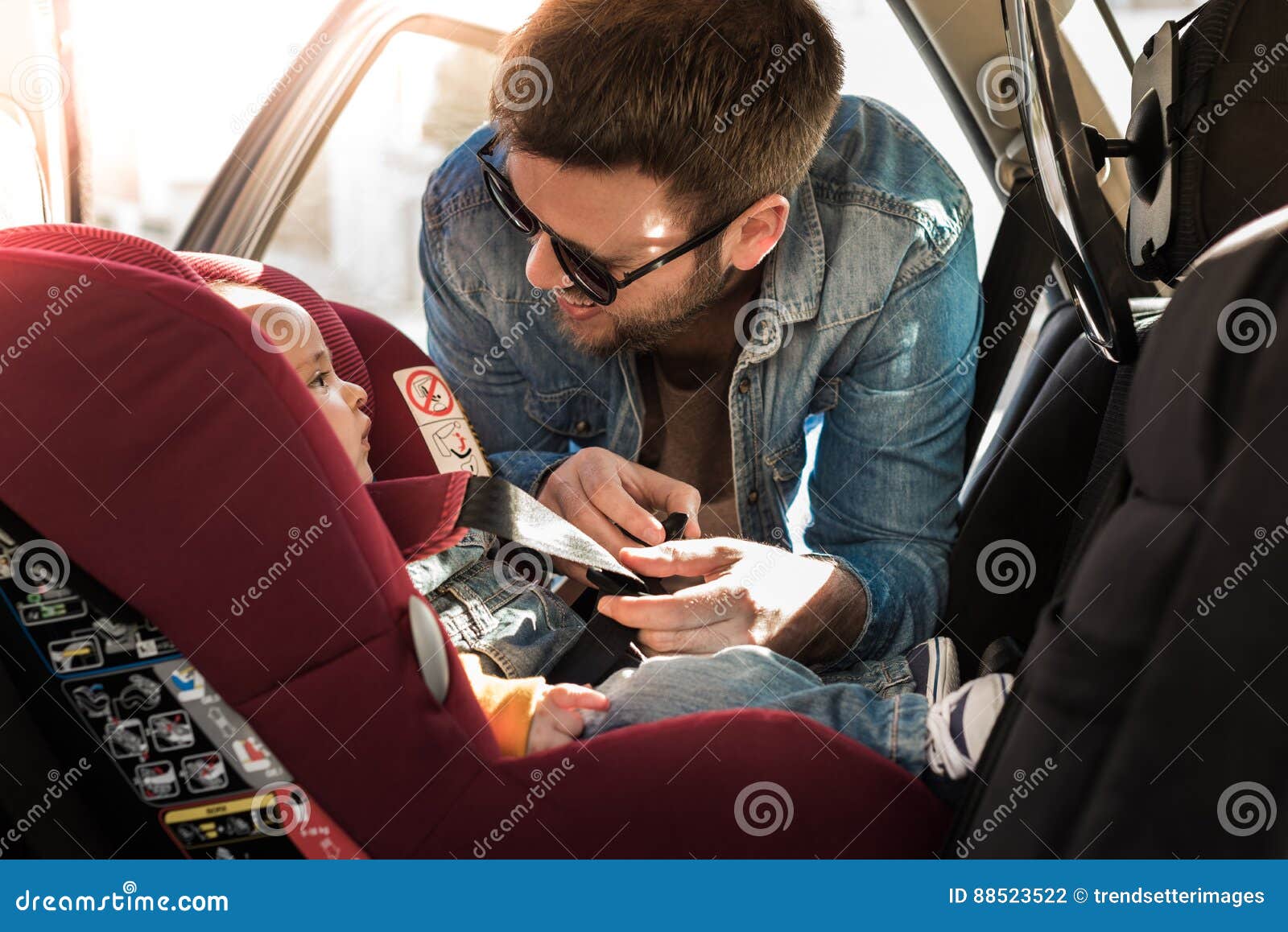 father fasten his baby in car seat