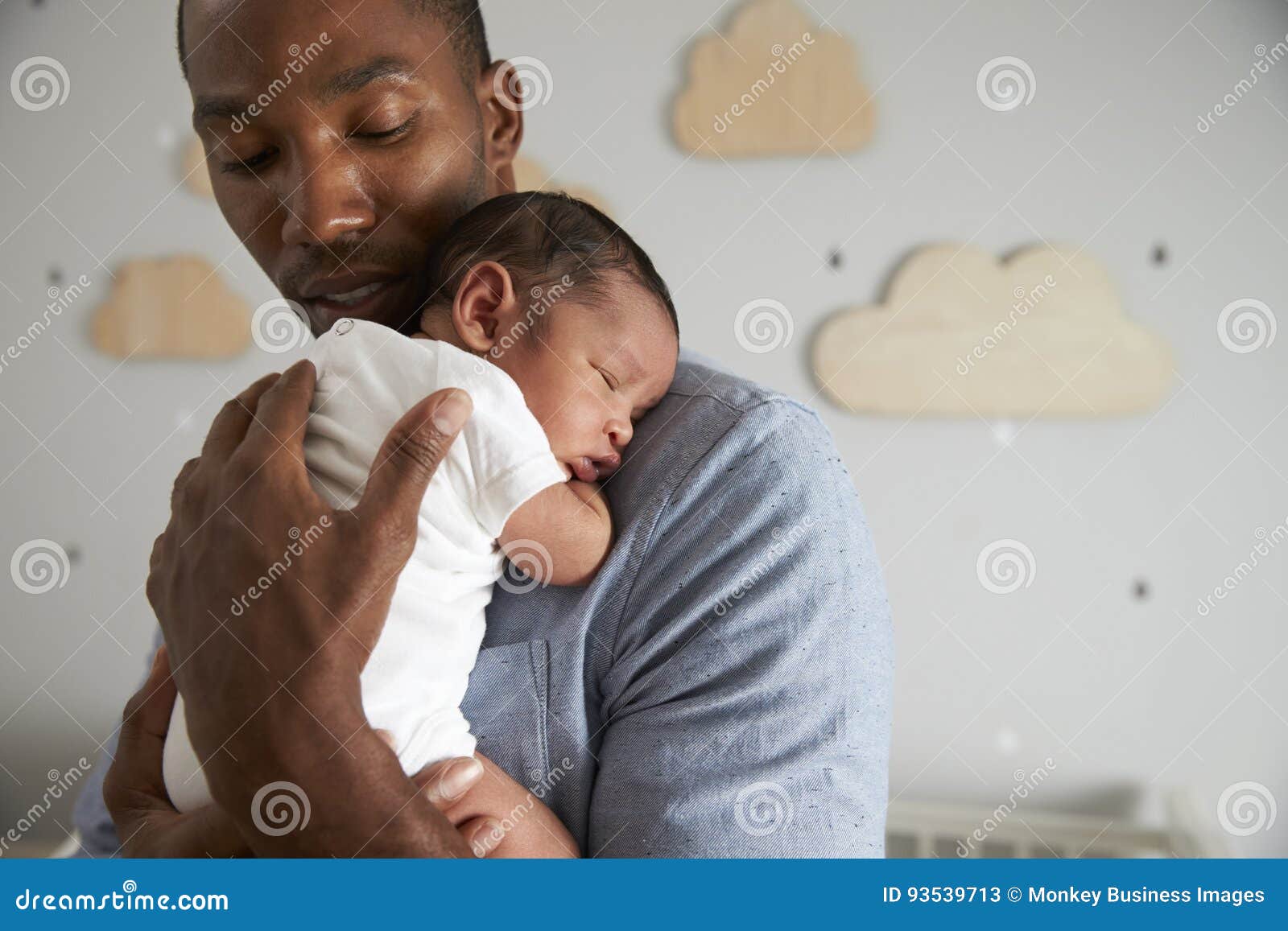 father holding newborn baby son in nursery