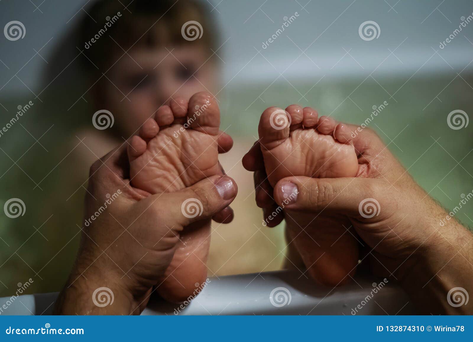 Father holds baby heels with love in bathroom with love and tenderness