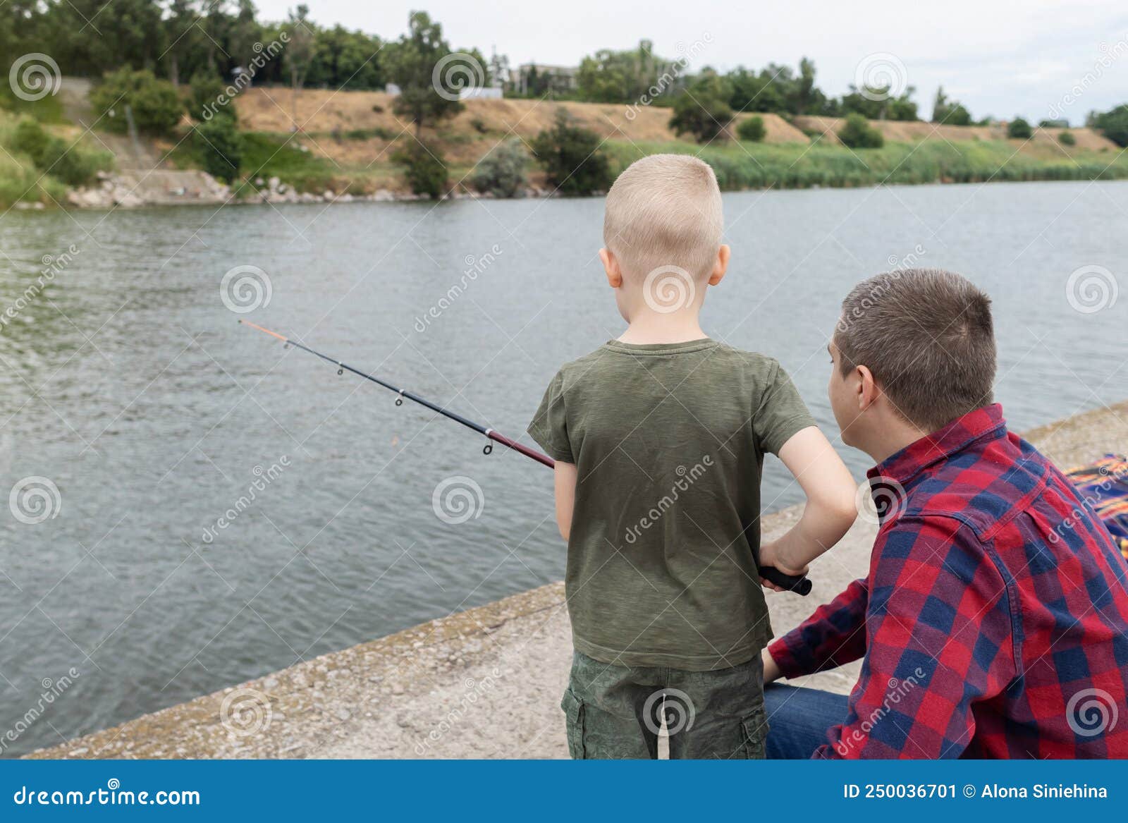 Father and Son Fishing. Dad Shows His Son How To Hold the Spinning