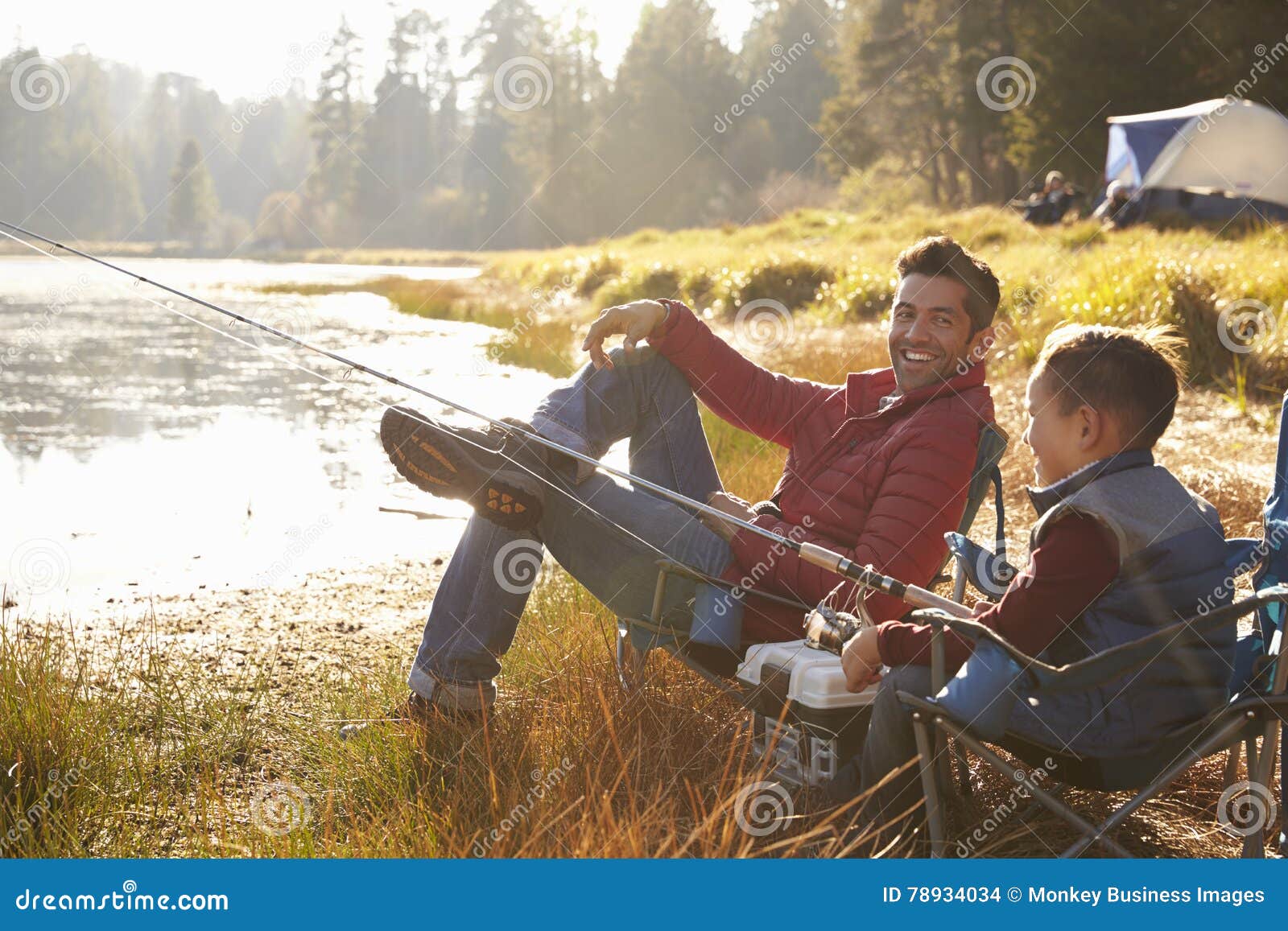 father and son fishing by a lake, dad looks to camera
