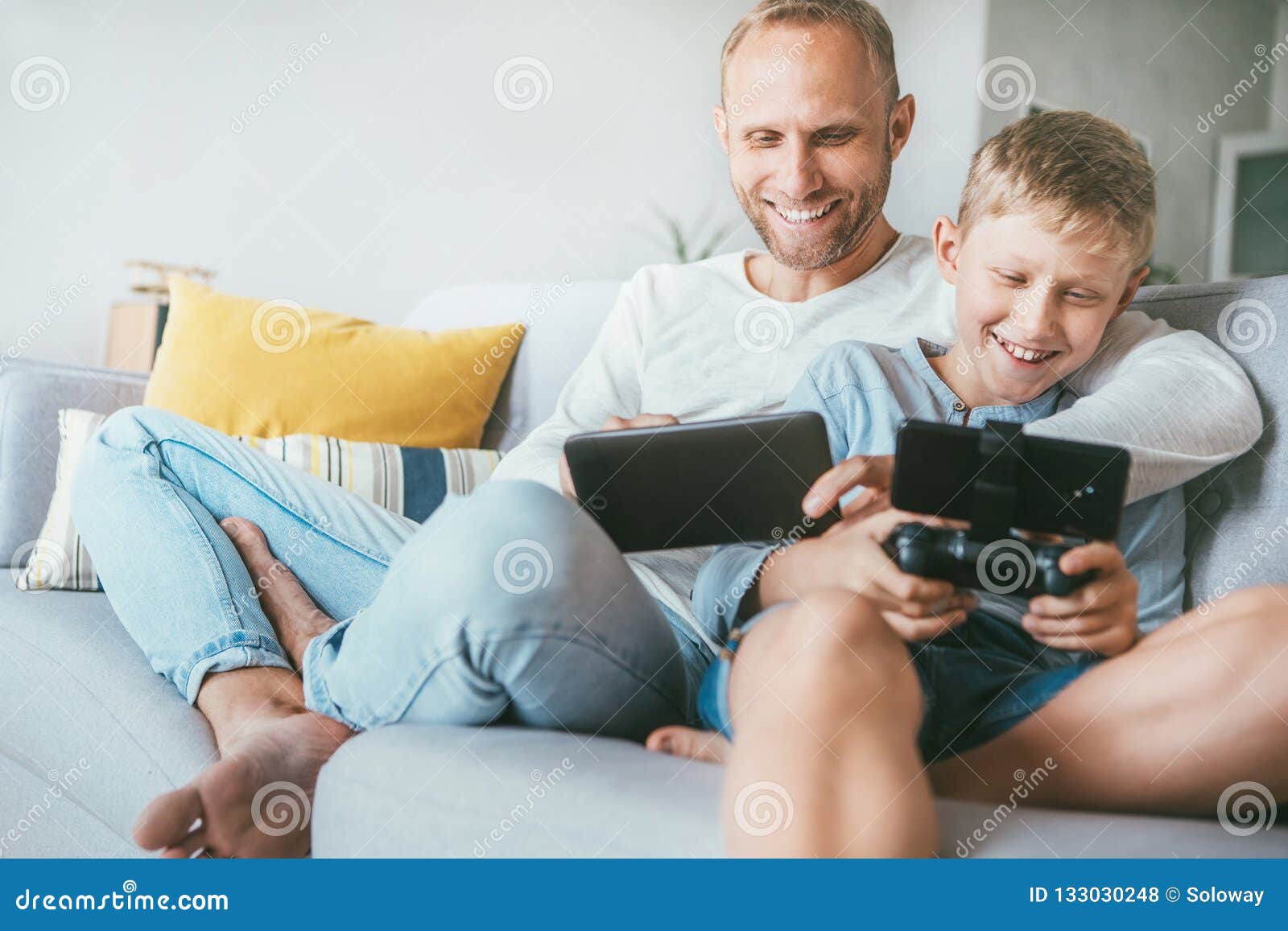 father and son game players funs sit together at home on cozy so