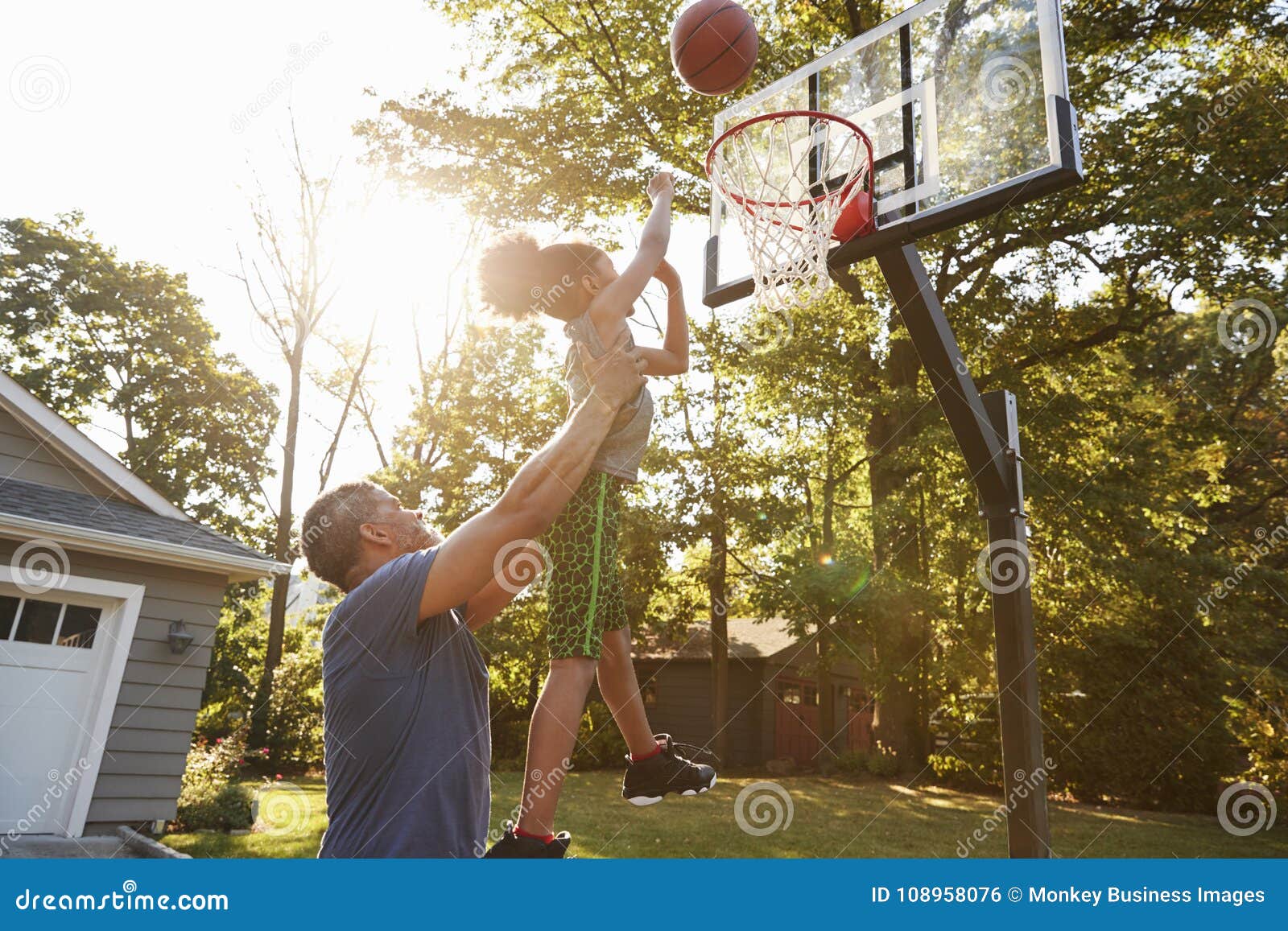 father and son playing basketball on driveway at home