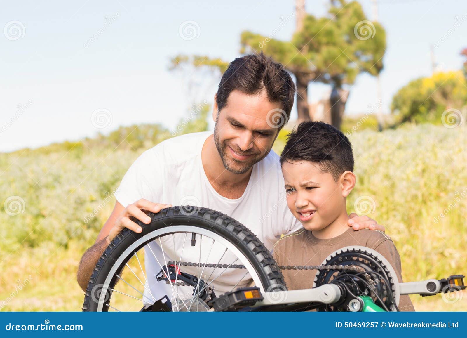 Father and son repairing bike together on a sunny day